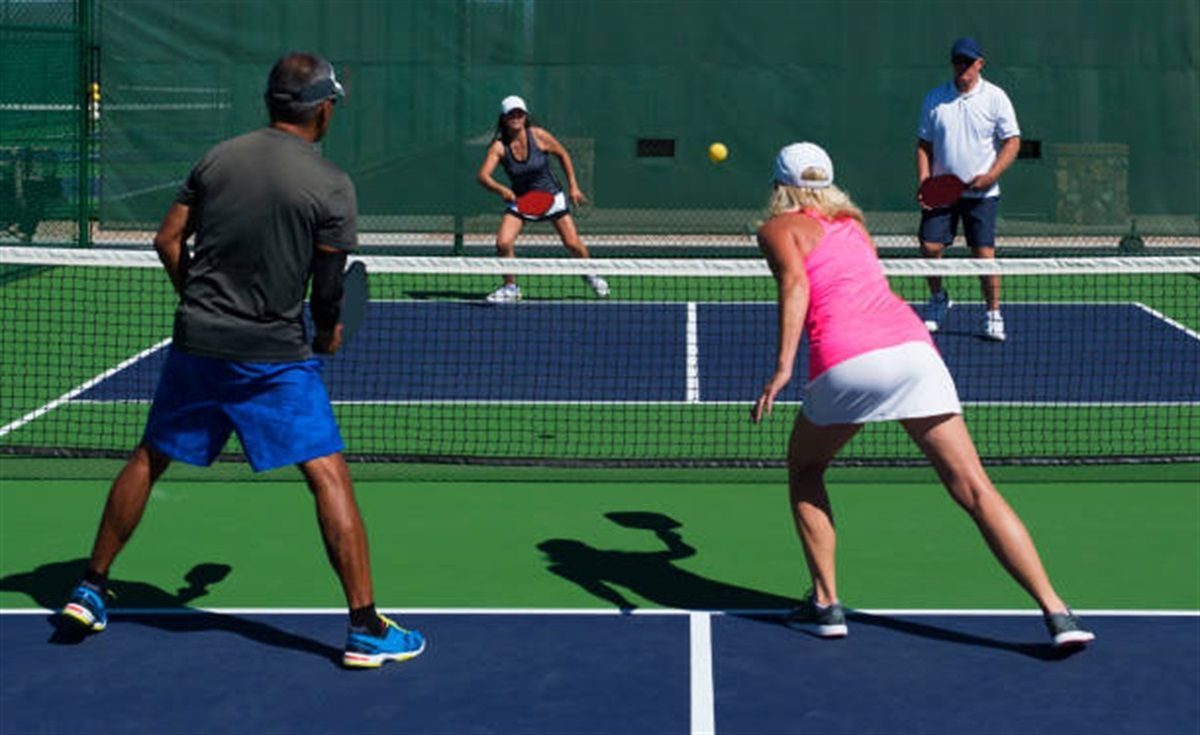 A group of people are playing tennis on a tennis court.