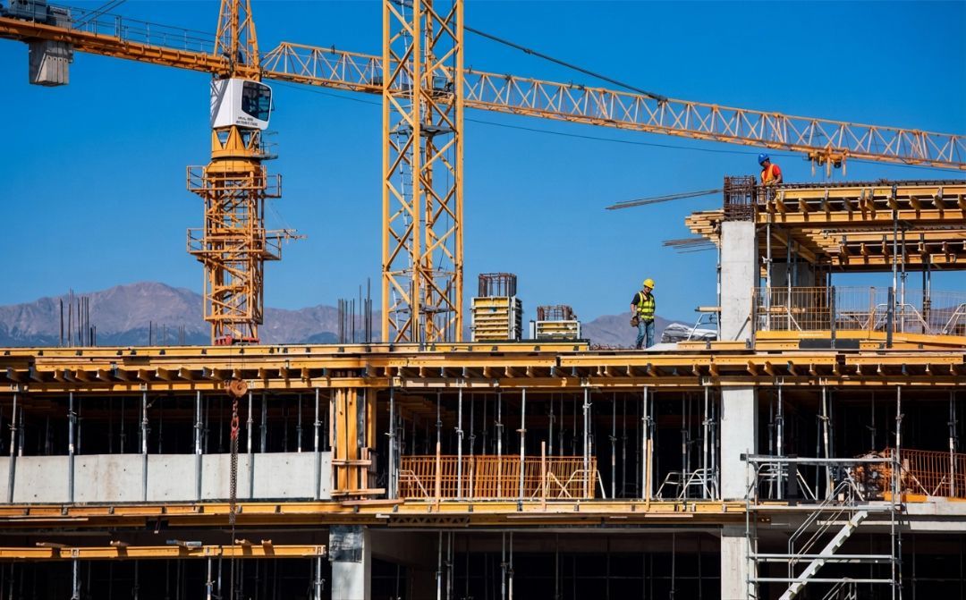 Construction workers and cranes building a modern structure in Colorado USA under bright high-altitu