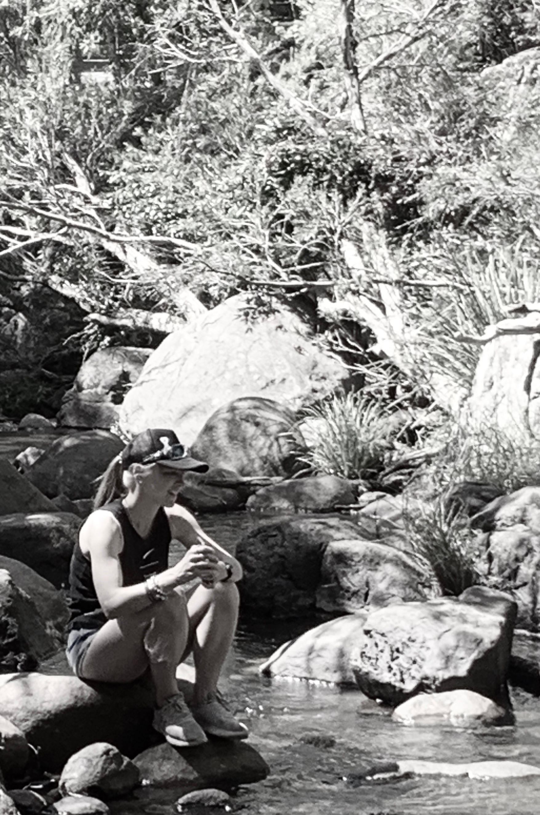 A woman is sitting on a rock near a river.