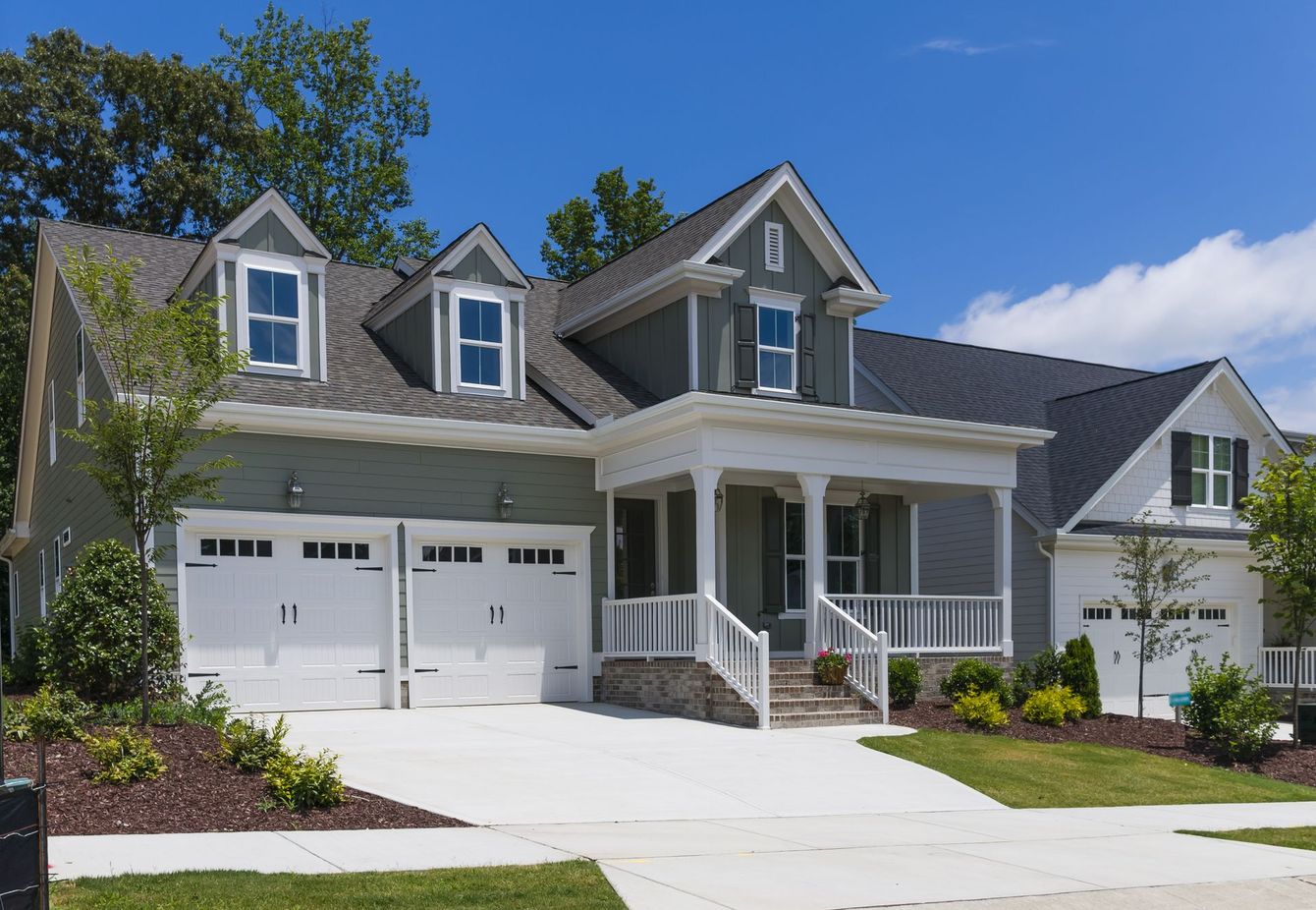 A large house with two garages and a porch on a sunny day
