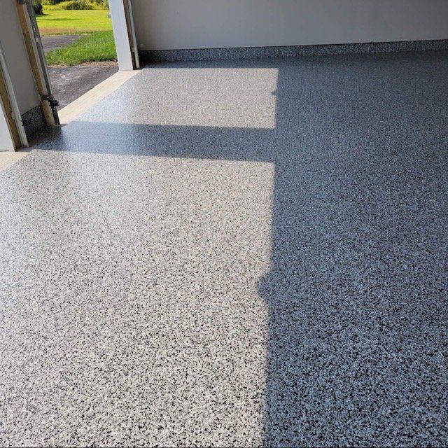 A close-up view of a newly installed, light grey speckled epoxy garage floor finish.