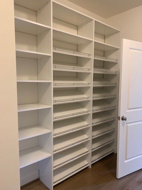A white, wall-mounted closet shelving unit with one section of solid shelves and two sections featuring tilted racks.