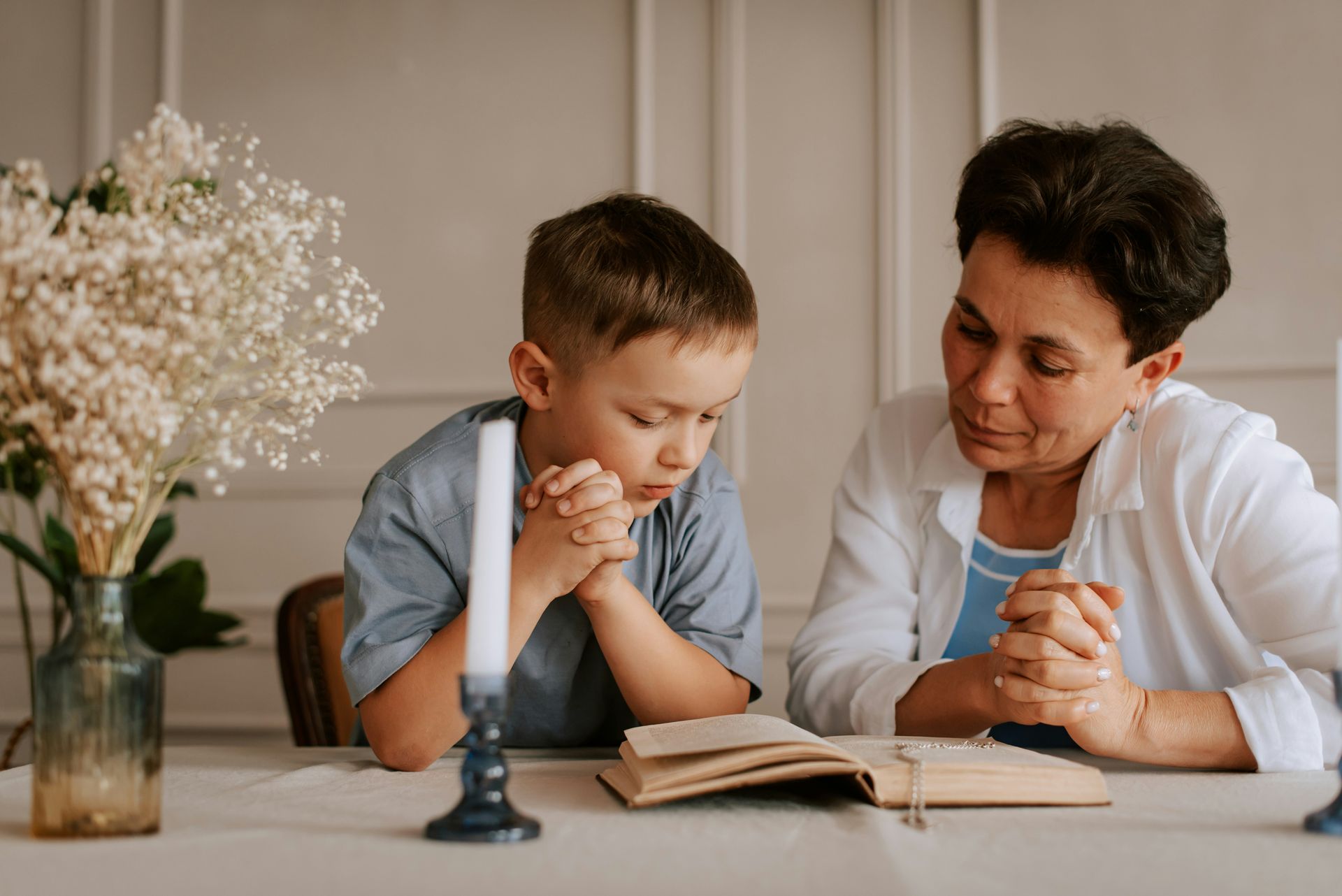 Adult and child reading together at a table with an open book and candlestick