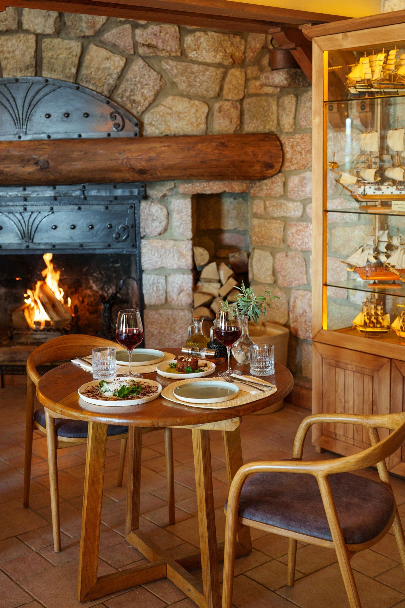 Manzara Boutique Hotel |Cozy stone fireplace dining nook with set table and wooden chairs