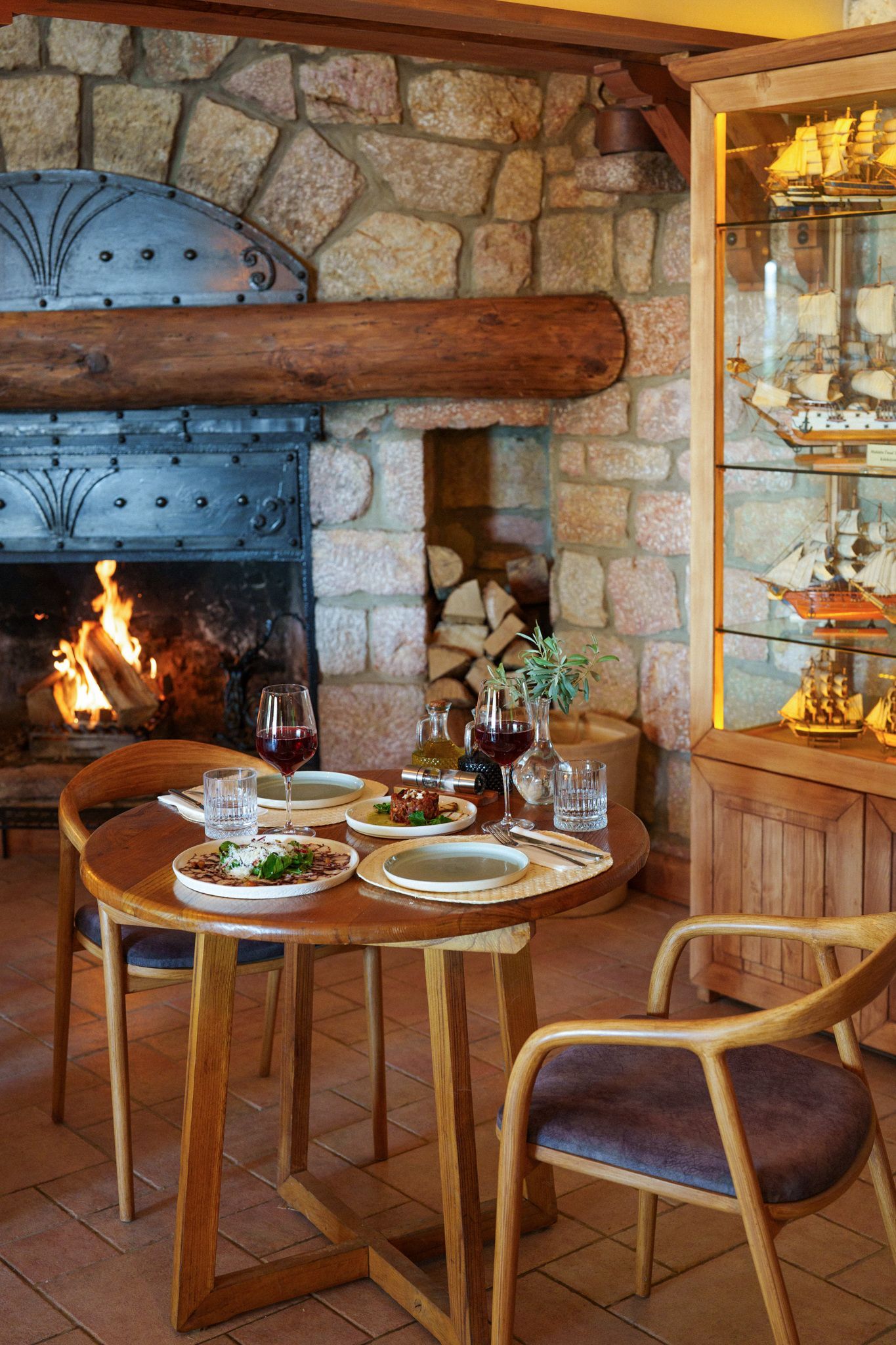 Manzara Boutique Hotel | Cozy stone fireplace dining nook with a set table, wooden chairs, and warm rustic decor