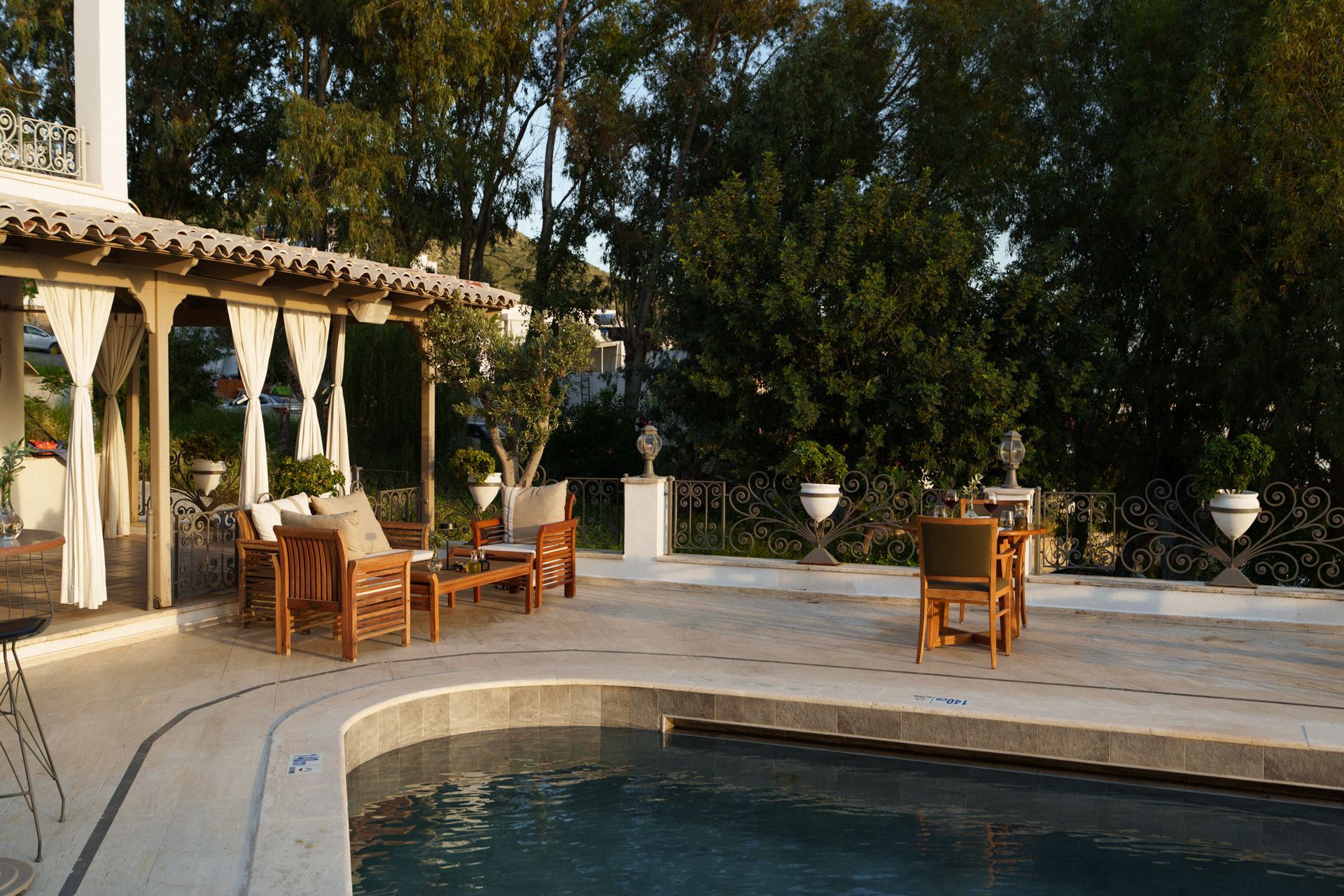 Manzara Boutique Hotel | Patio with outdoor seating beside a curved swimming pool, shaded by trees and a white pergola.