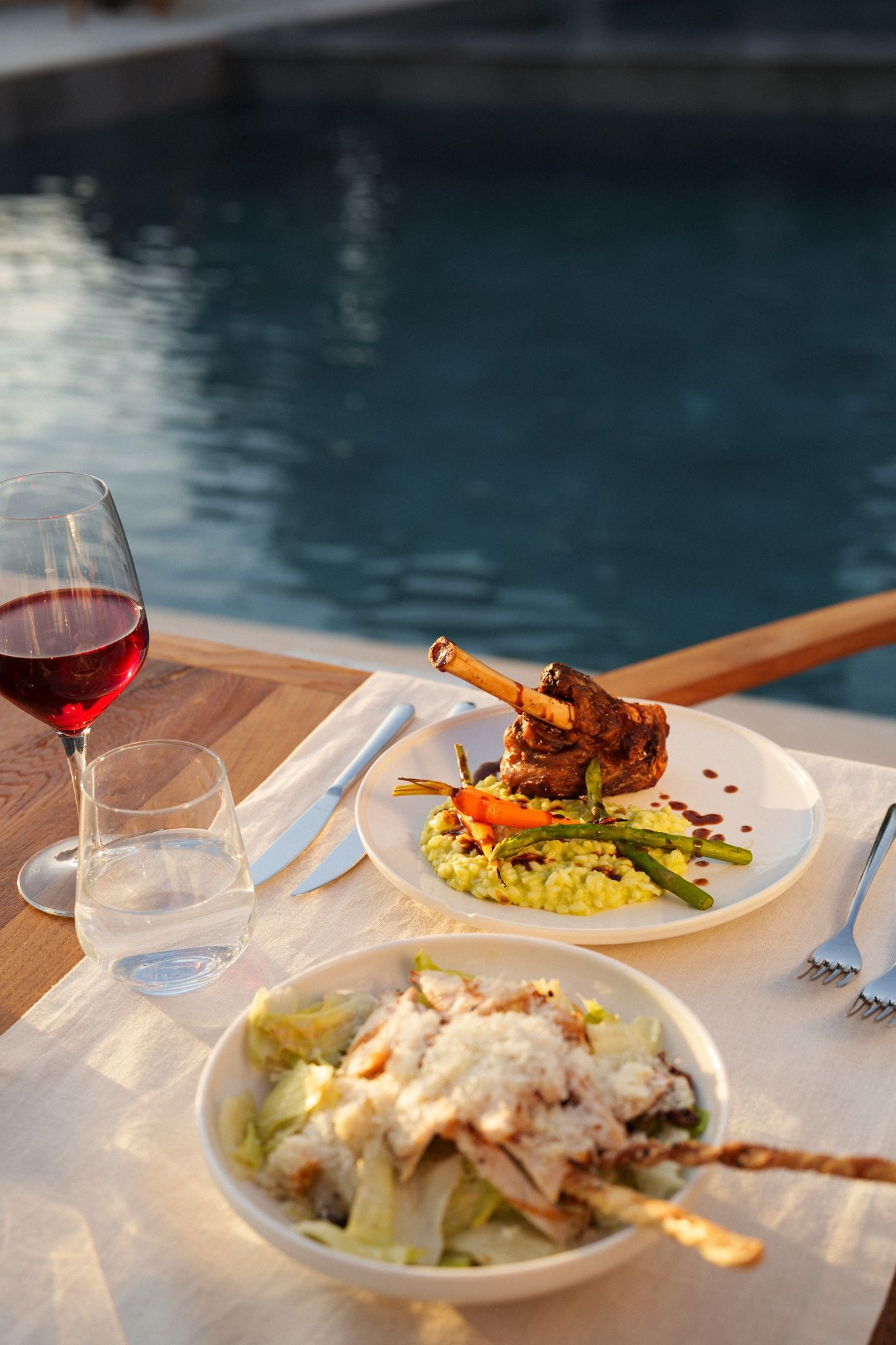 Manzara Boutique Hotel | Poolside table with wine, salad, and seafood plates beside a blue swimming pool