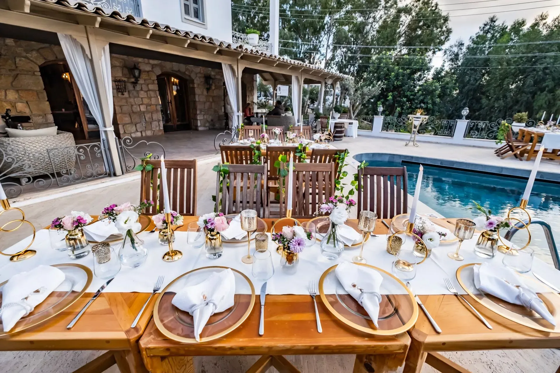 Manzara Boutique Hotel | Set outdoor dining table beside a pool with plates, glassware, and floral centerpieces.