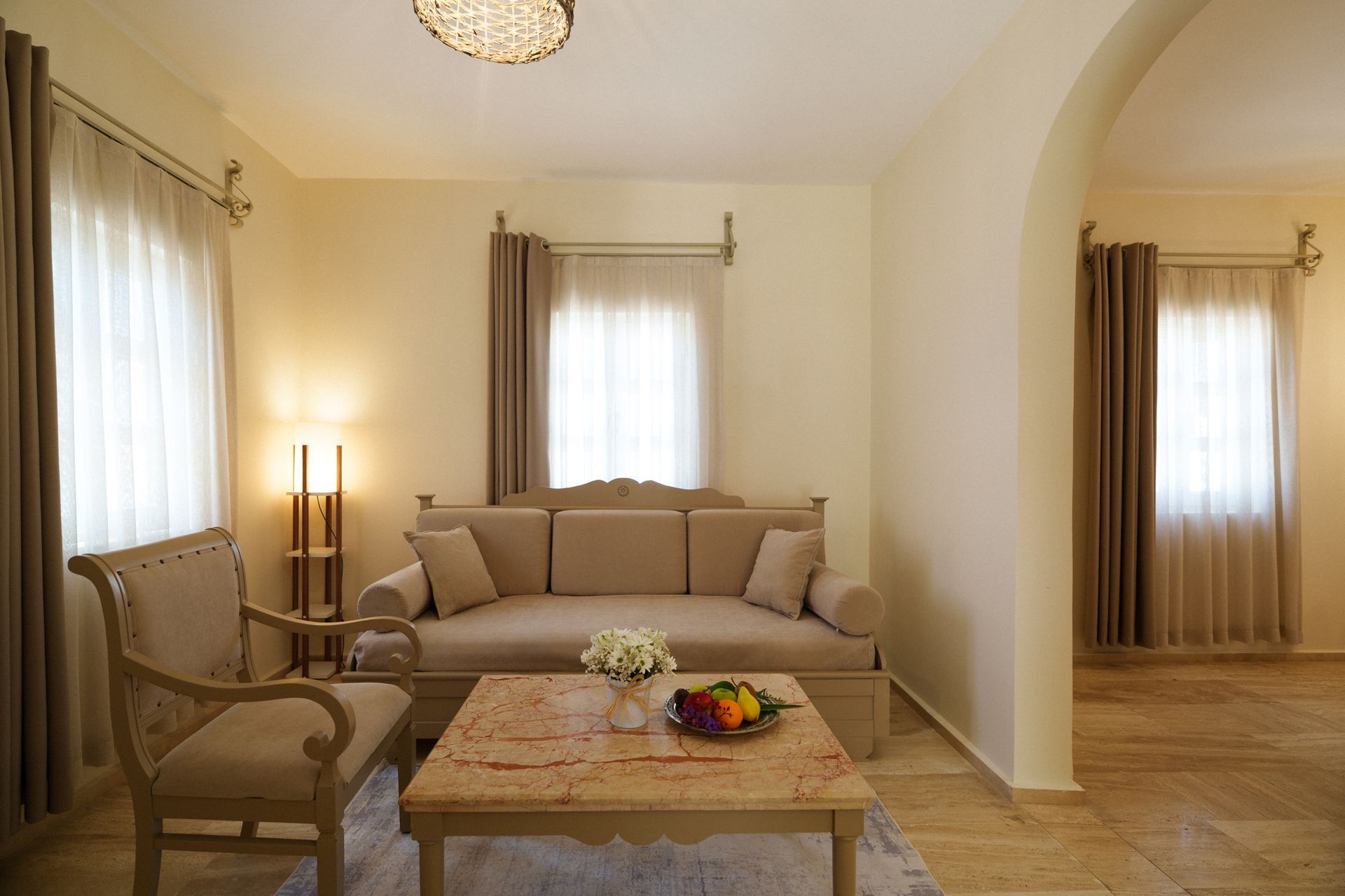 Manzara Boutique Hotel | Bright living room with beige sofa, armchair, coffee table, and large curtained windows