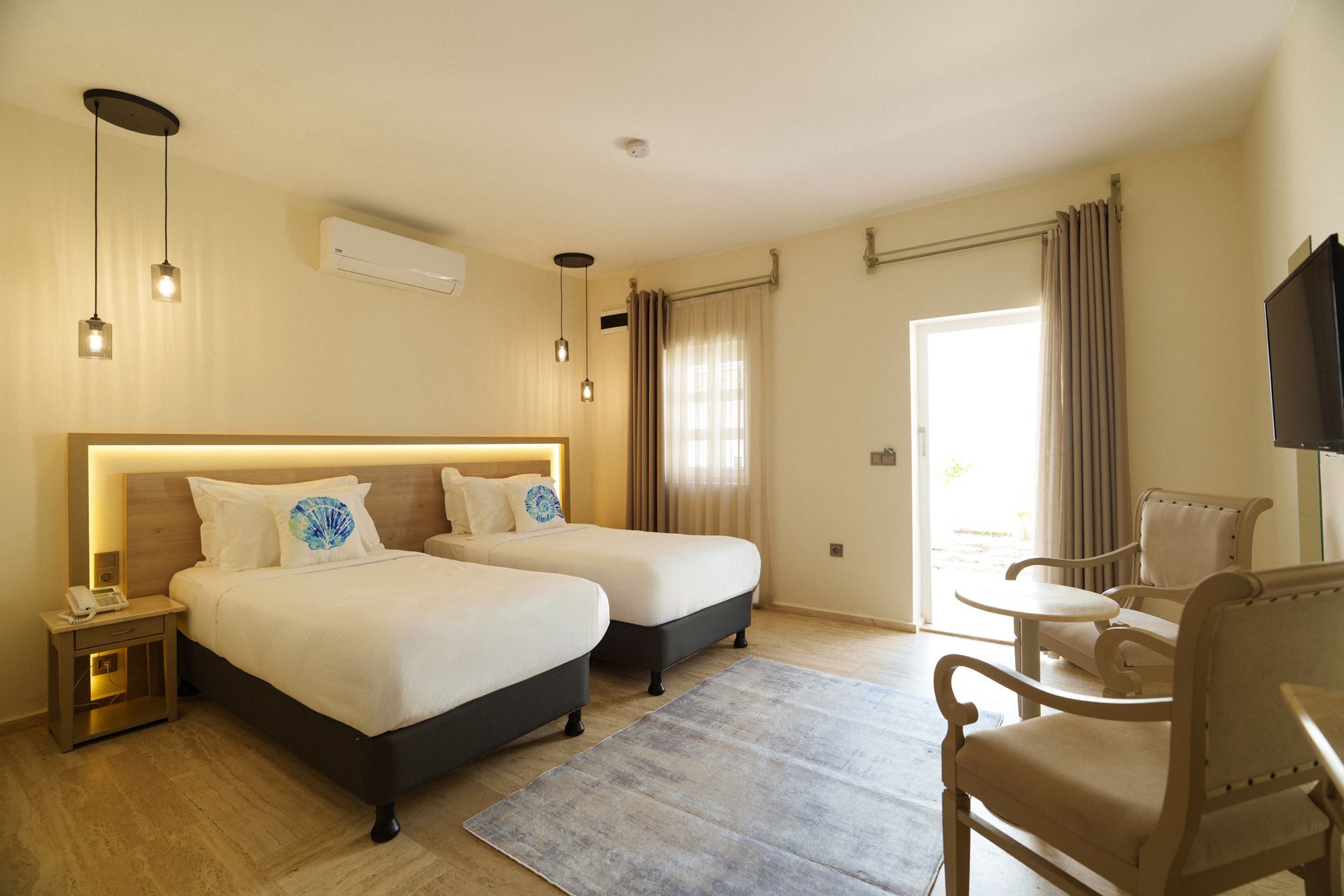 Manzara Boutique Hotel | Bright hotel room with two twin beds, soft lighting, a window, and a chair by the door.