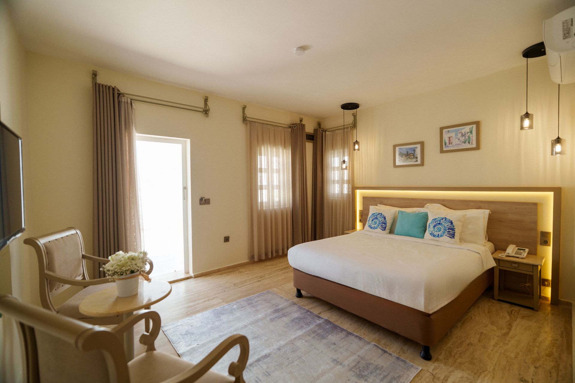 Manzara Boutique Hotel | Bright bedroom with a queen bed, armchair, rug, and soft beige curtains and lighting