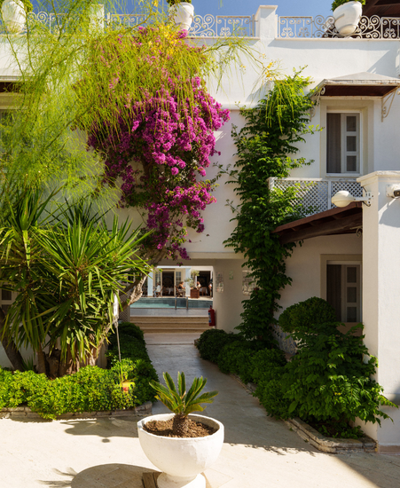 Manzara Boutique Hotel |  White Mediterranean-style house with lush bougainvillea, vines
