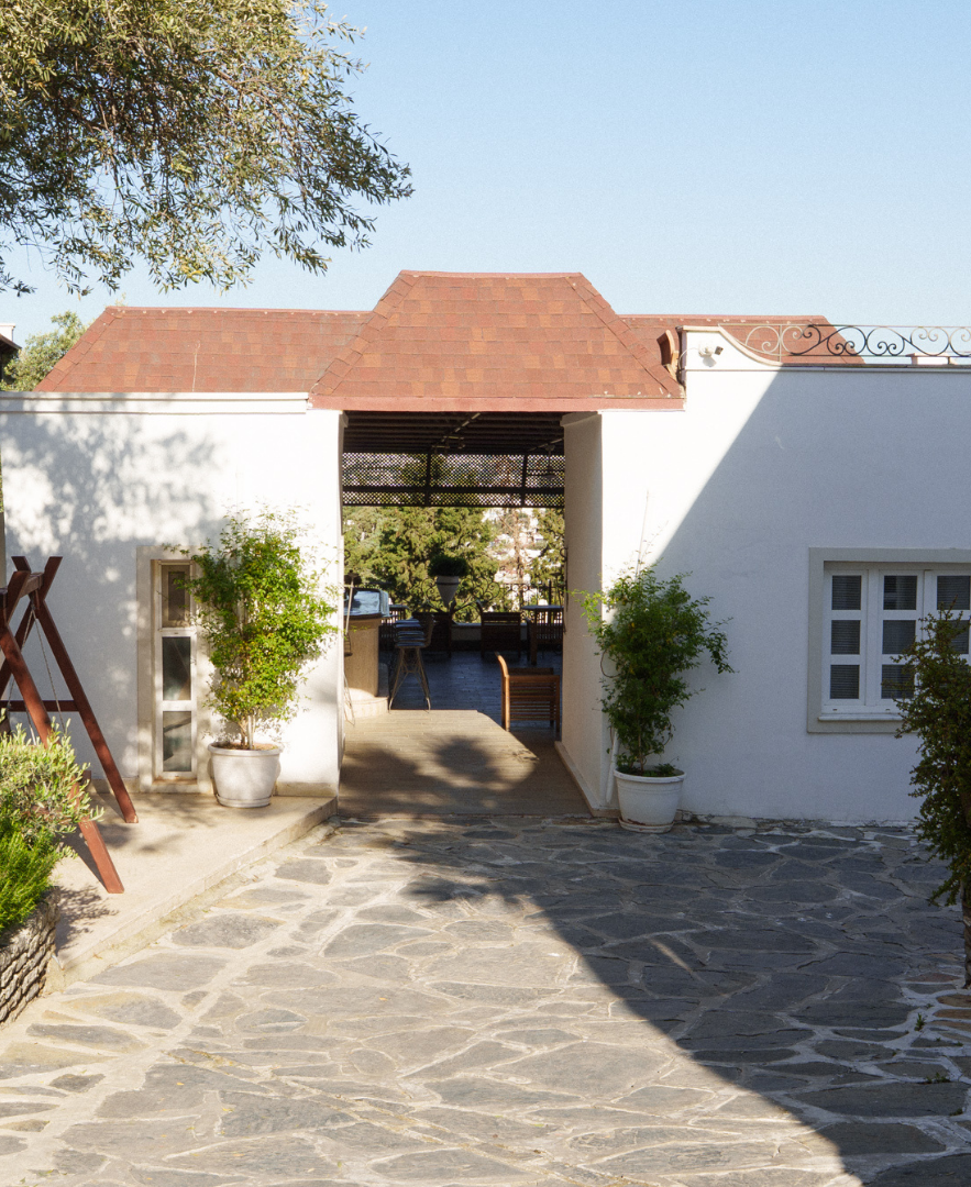 Manzara Boutique Hotel Garden, Stone courtyard leading to a white building entrance with a red-tiled roof and potted plants
