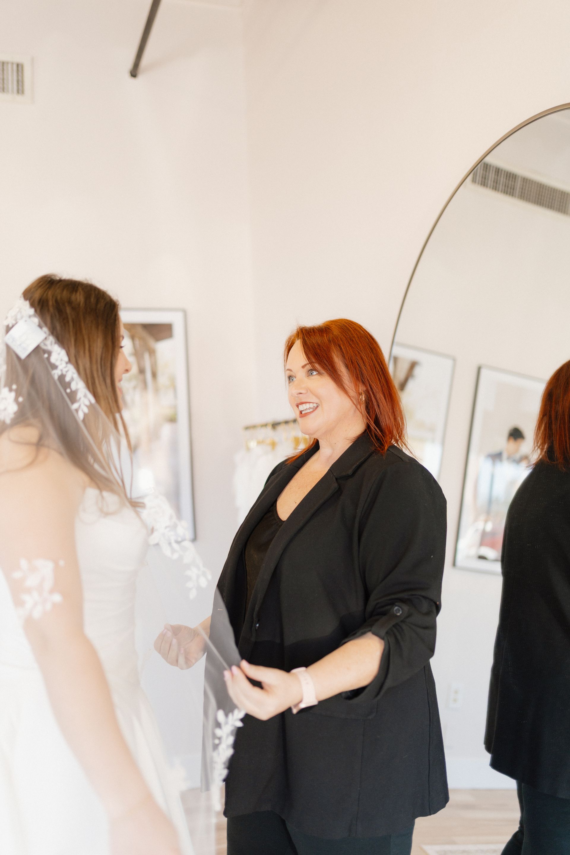 Woman in a white off-the-shoulder dress standing indoors against a beige wall.