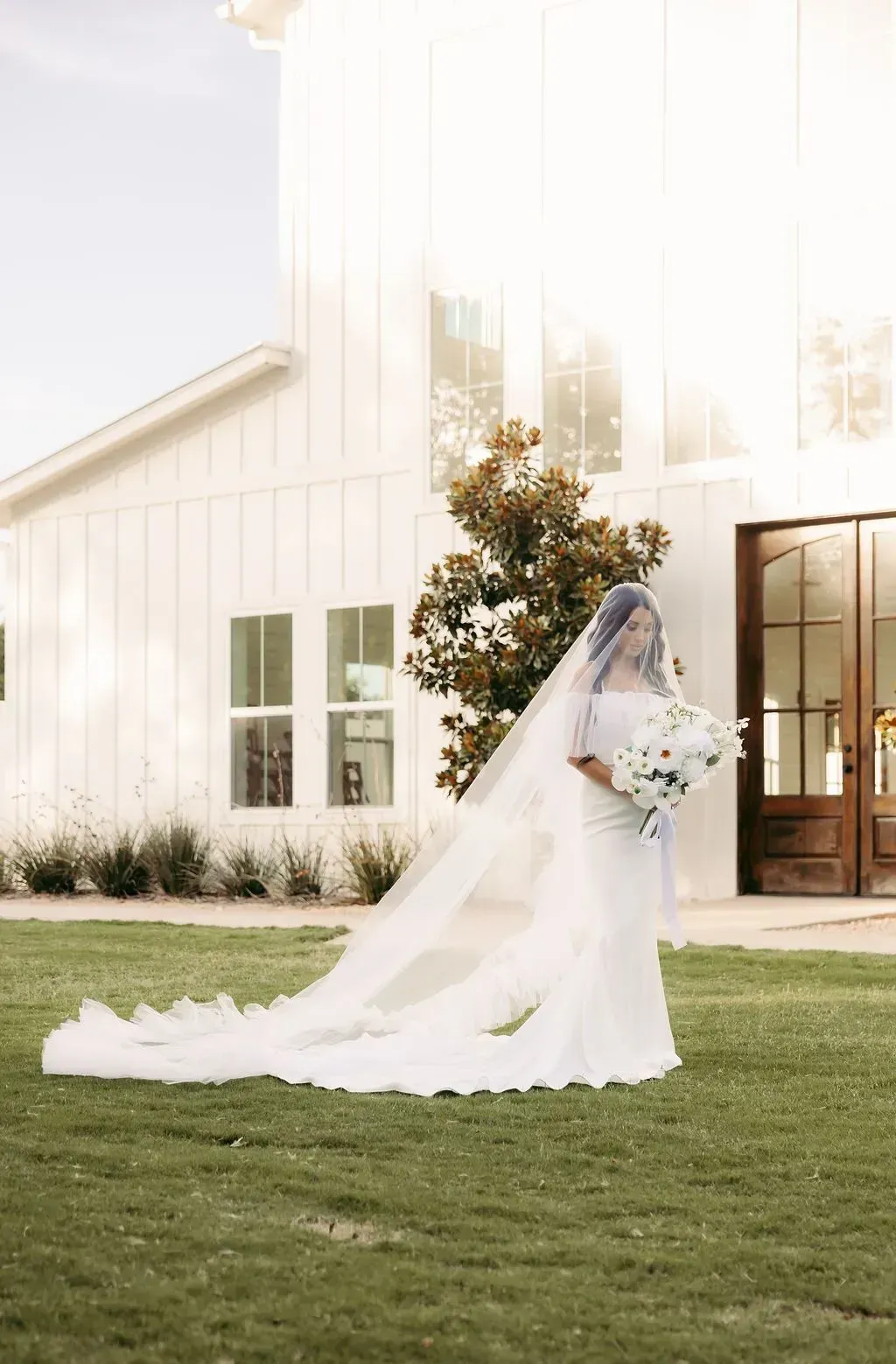 The bride is wearing a long veil and holding a bouquet of flowers.