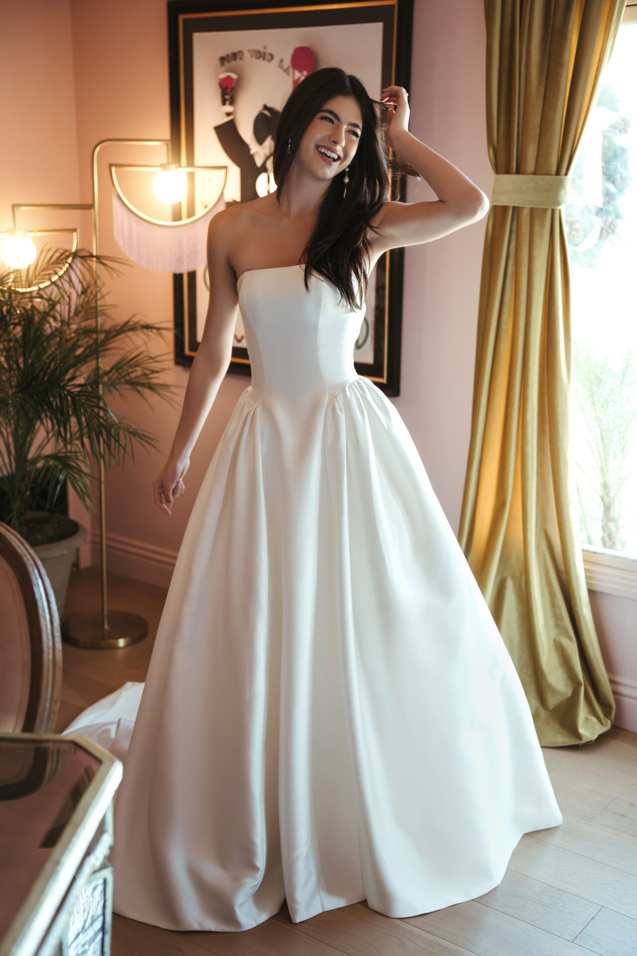 A woman in a white wedding dress is standing in front of a brick building.
