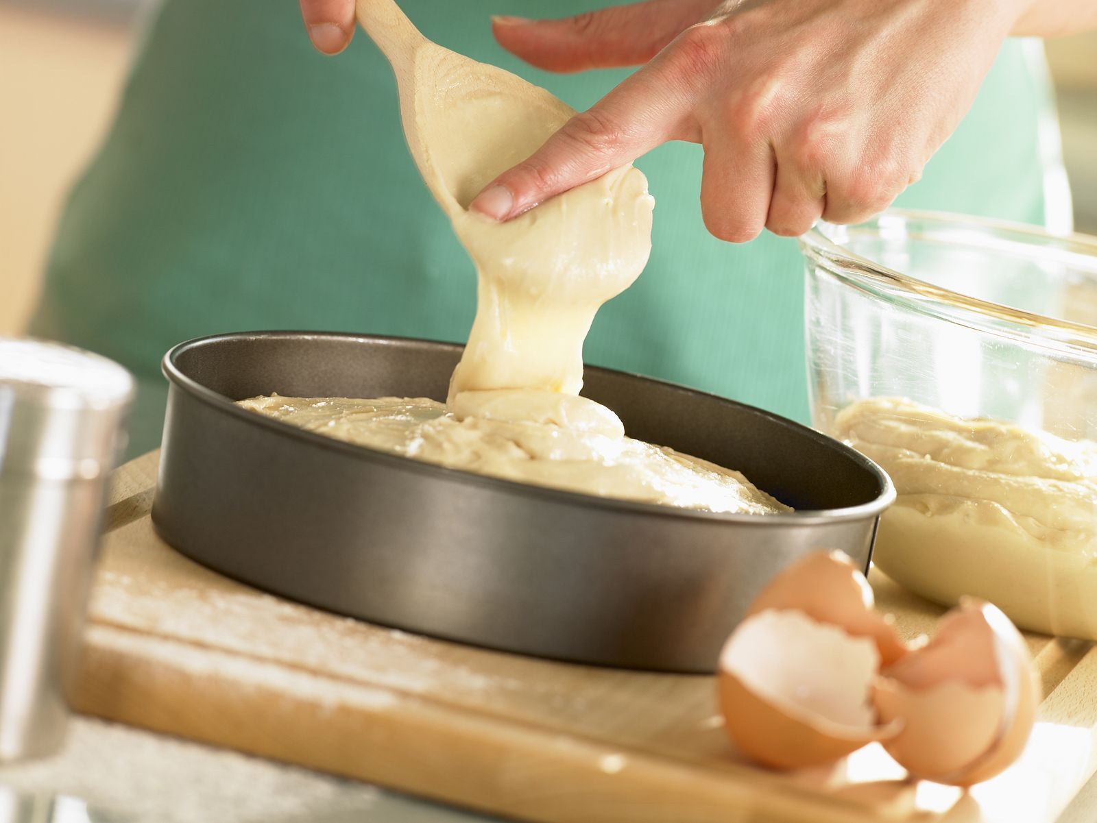 A person is pouring batter into a cake pan