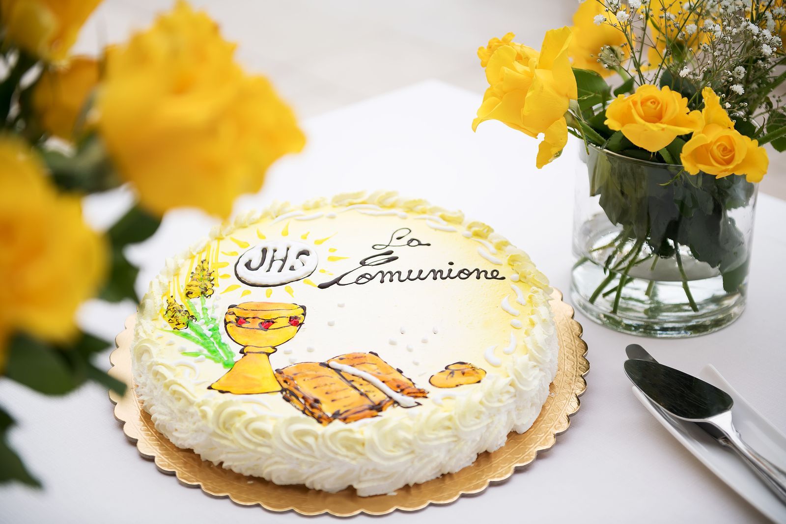 A cake on a table with a vase of yellow flowers in the background