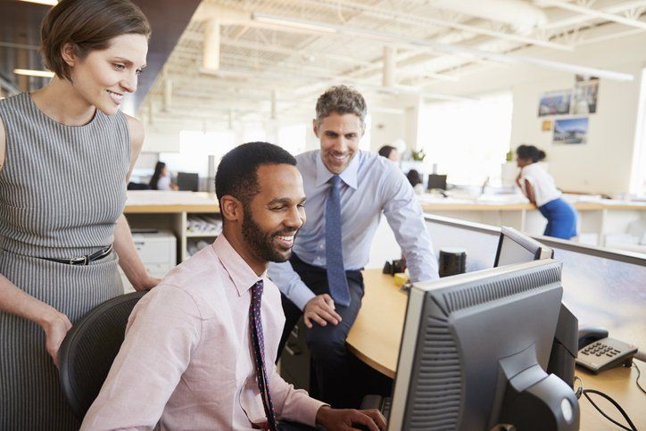 A group of people in an office smiling at a computer screen