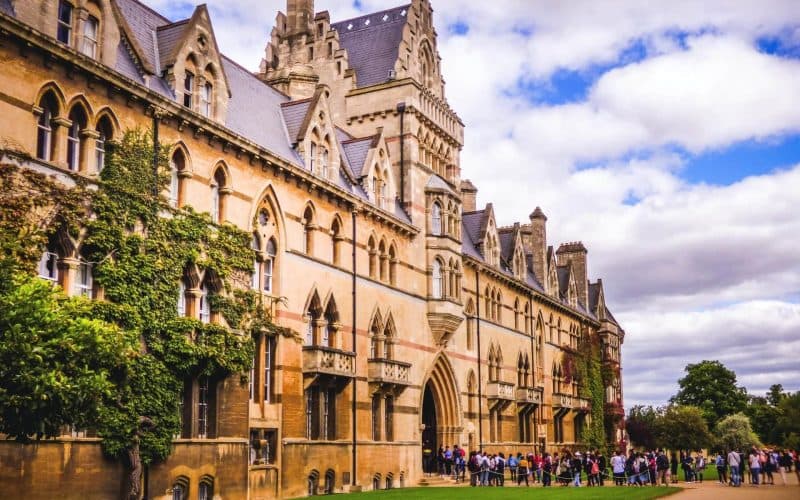 The front of a building on a college campus with people lined up to enter