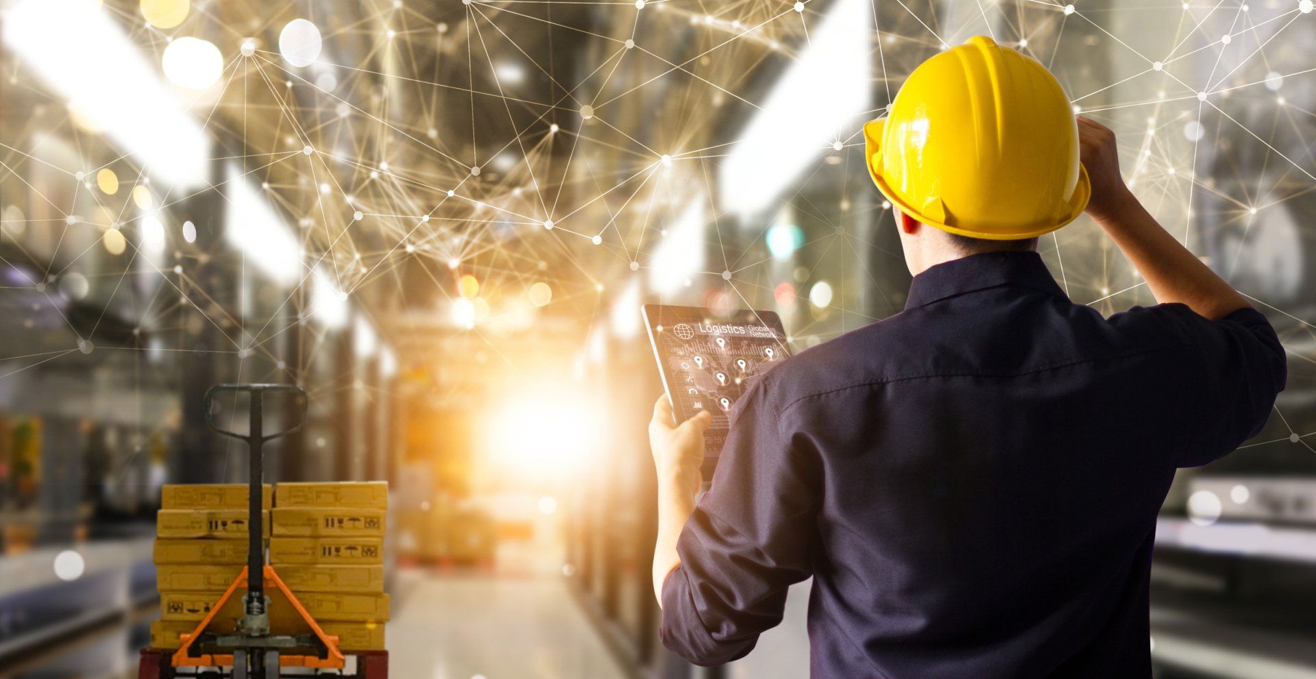A man standing in a warehouse and looking at logistics on an electronic device