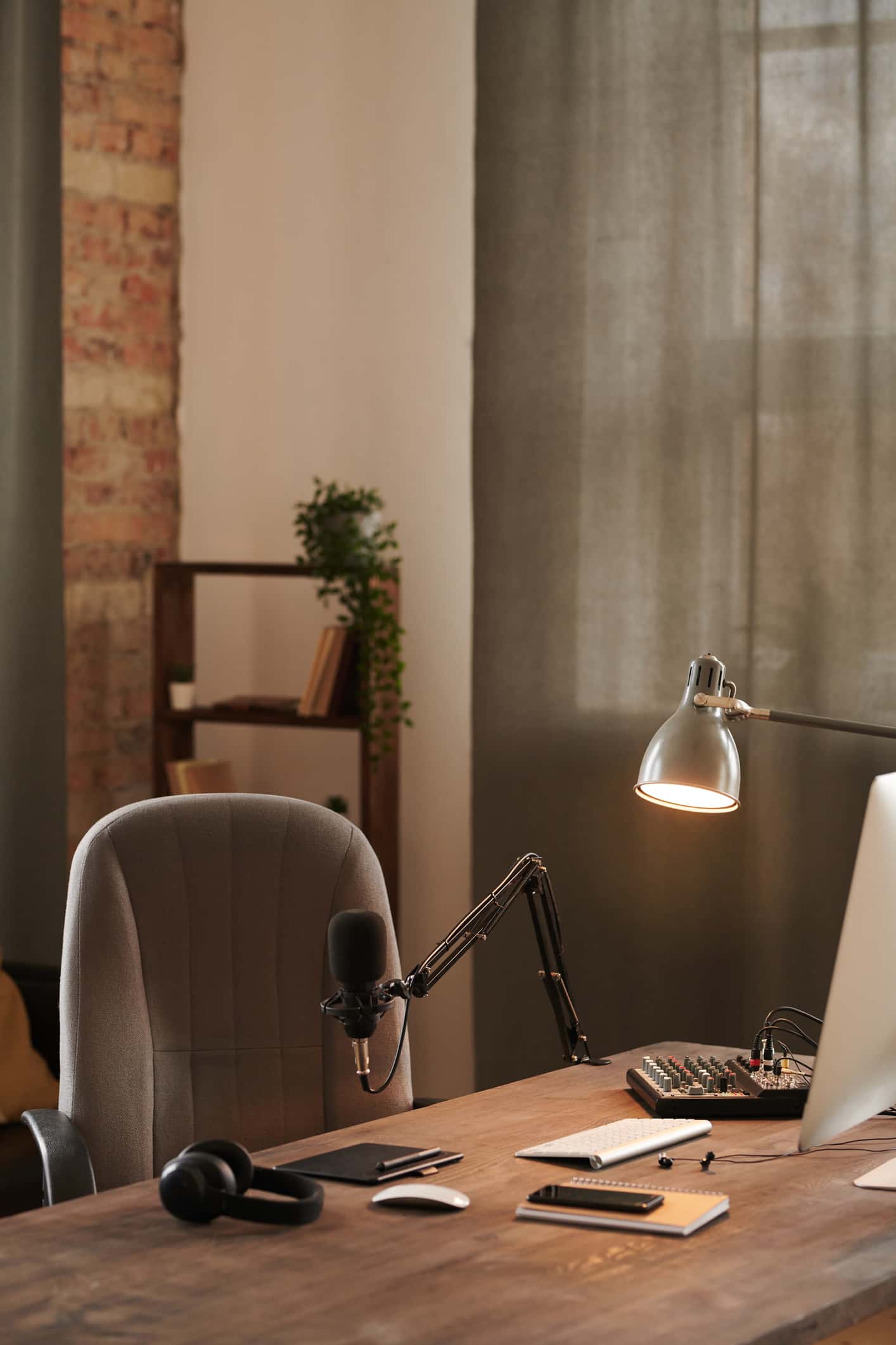 A desk with a lamp, microphone, headset, and other equipment