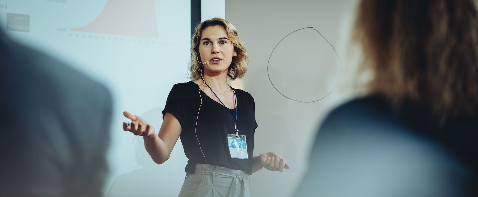A presenter speaking to an audience from a stage during a hybrid event