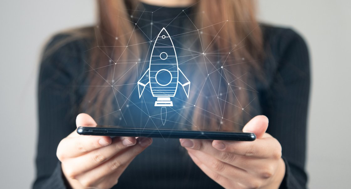 A woman holding an electronic device projecting an image of a rocket ship