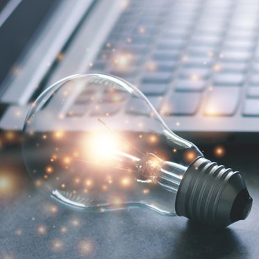 A lightbulb next to a keyboard emitting sparks