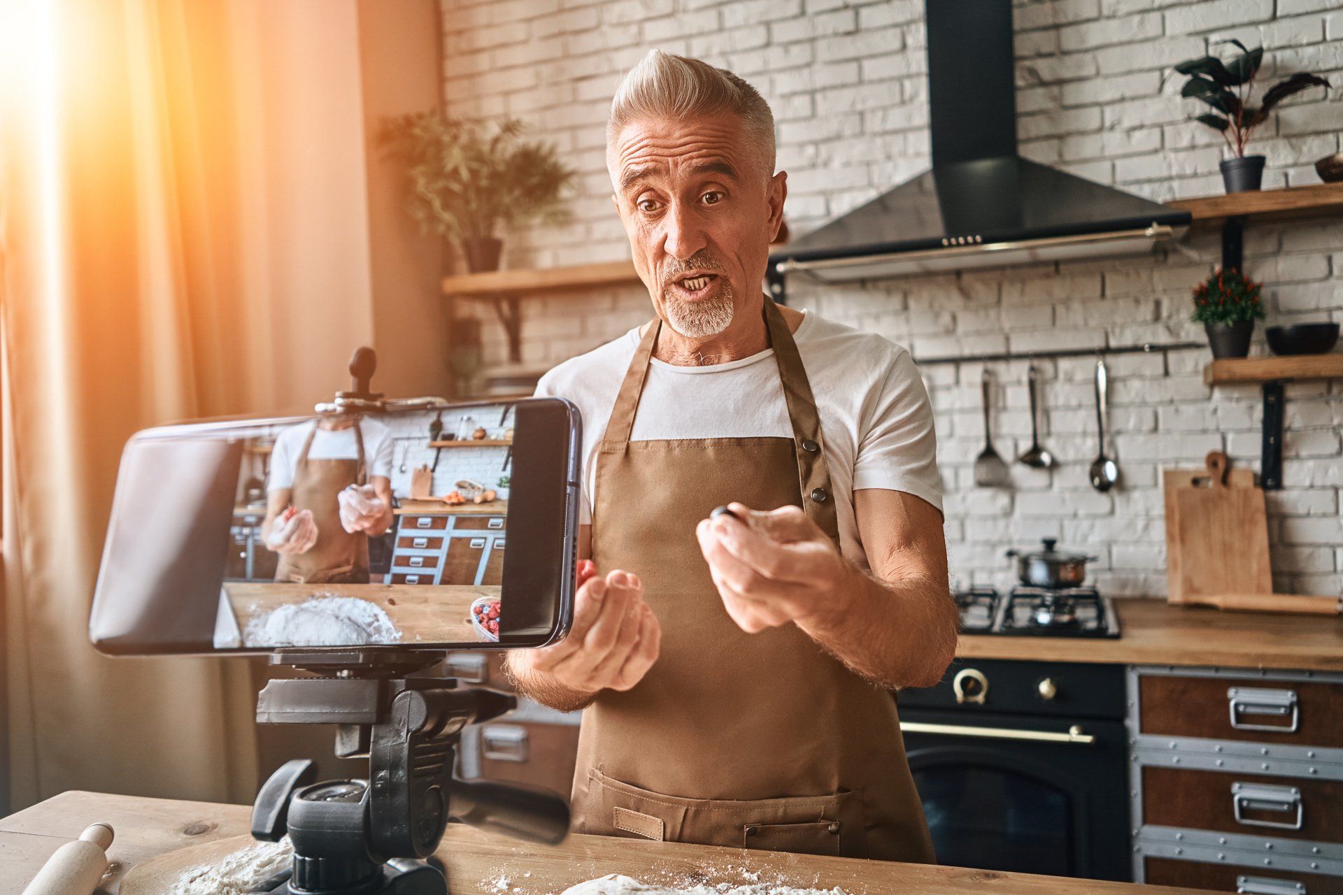 A man wearing an apron and standing in a kitchen participating in a virtual convention