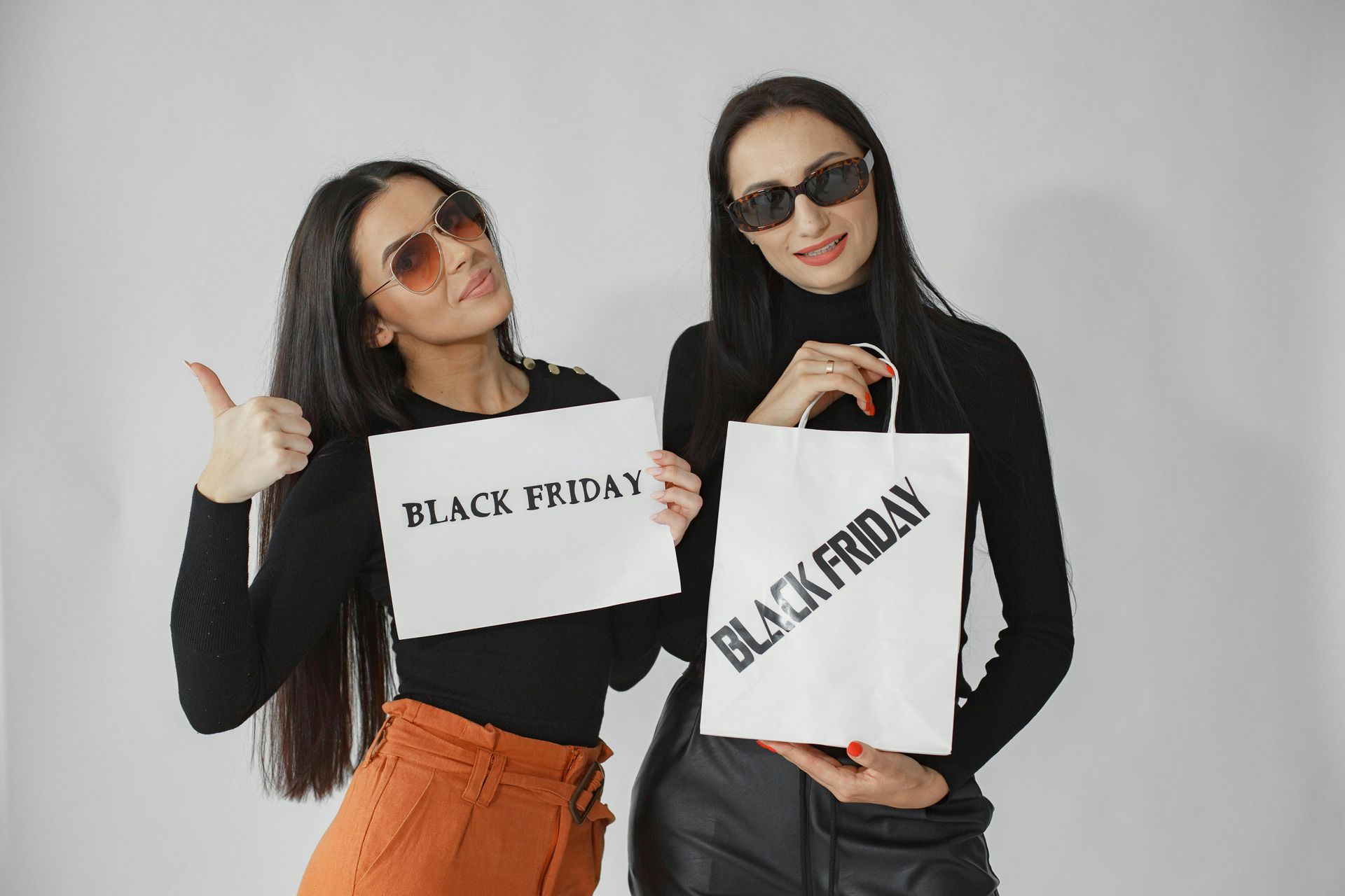 Zwei Frauen mit Sonnenbrille, eine mit erhobenen Daumen. In der Hand jeweils ein Goodie mit der Aufschrift