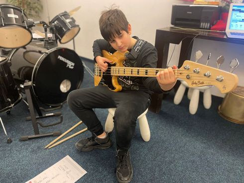 A young boy is sitting on a chair playing a guitar.