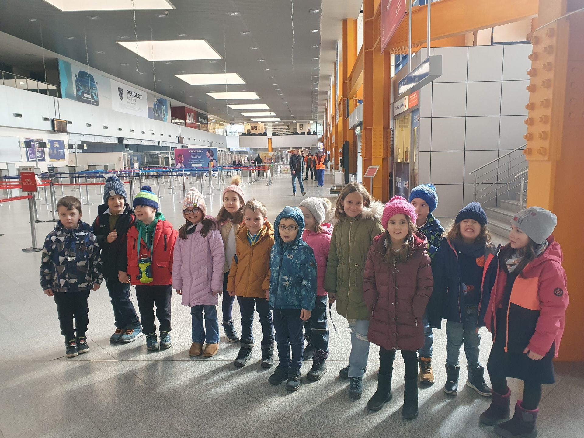 A group of children are posing for a picture in an airport.