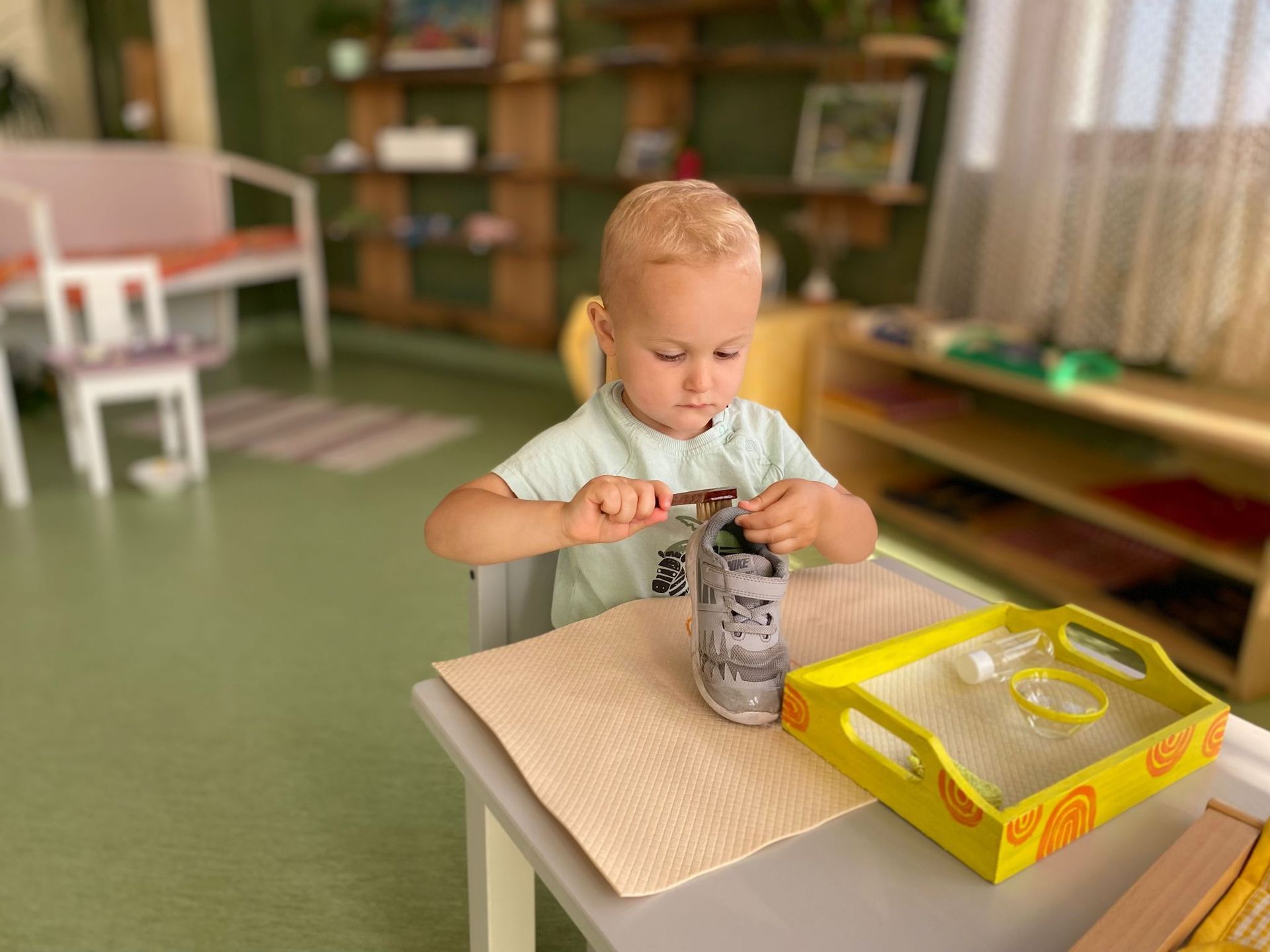 A young boy is sitting at a table playing with a can.