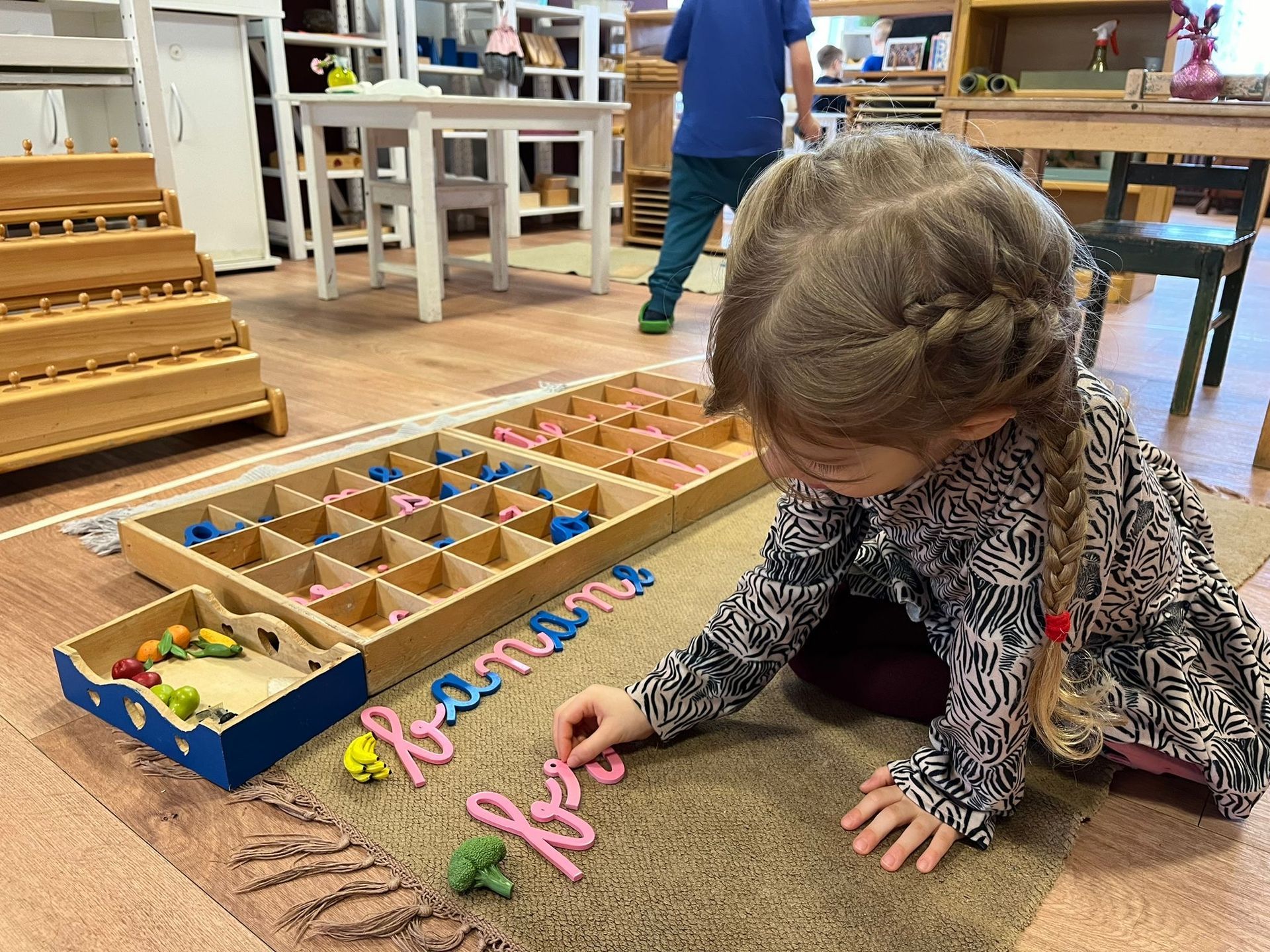 A little girl is sitting on the floor playing with letters and numbers.