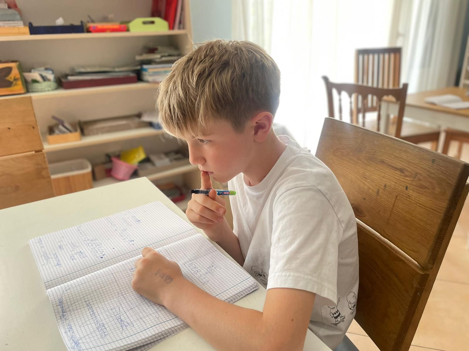 A young boy is sitting at a table doing his homework.