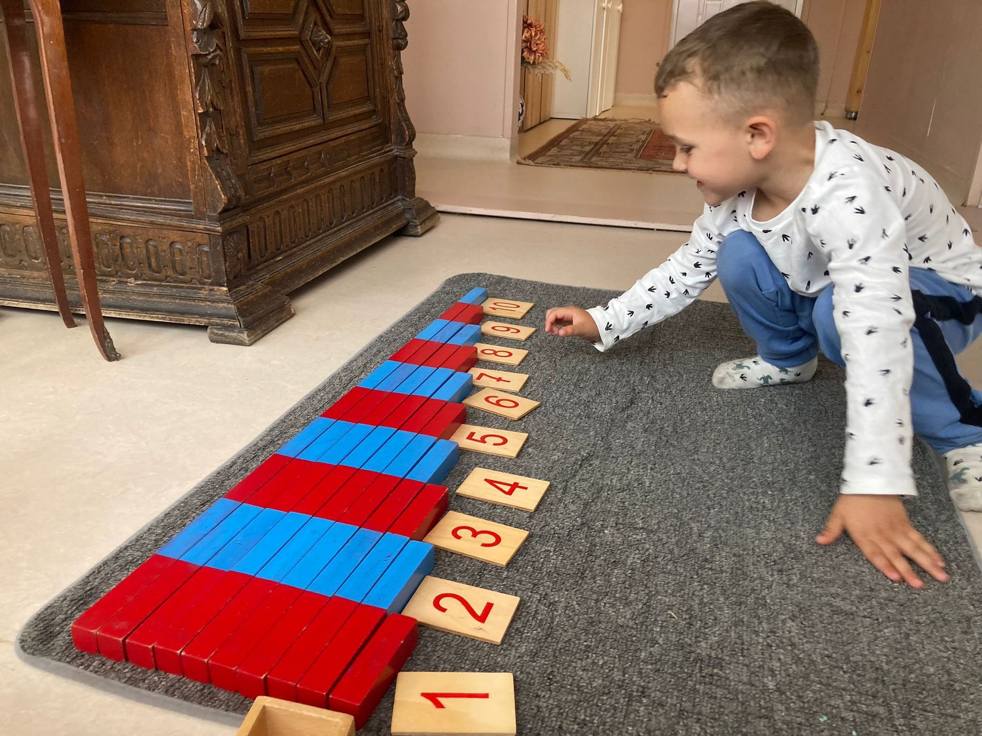 A young boy is playing with numbers on a rug.