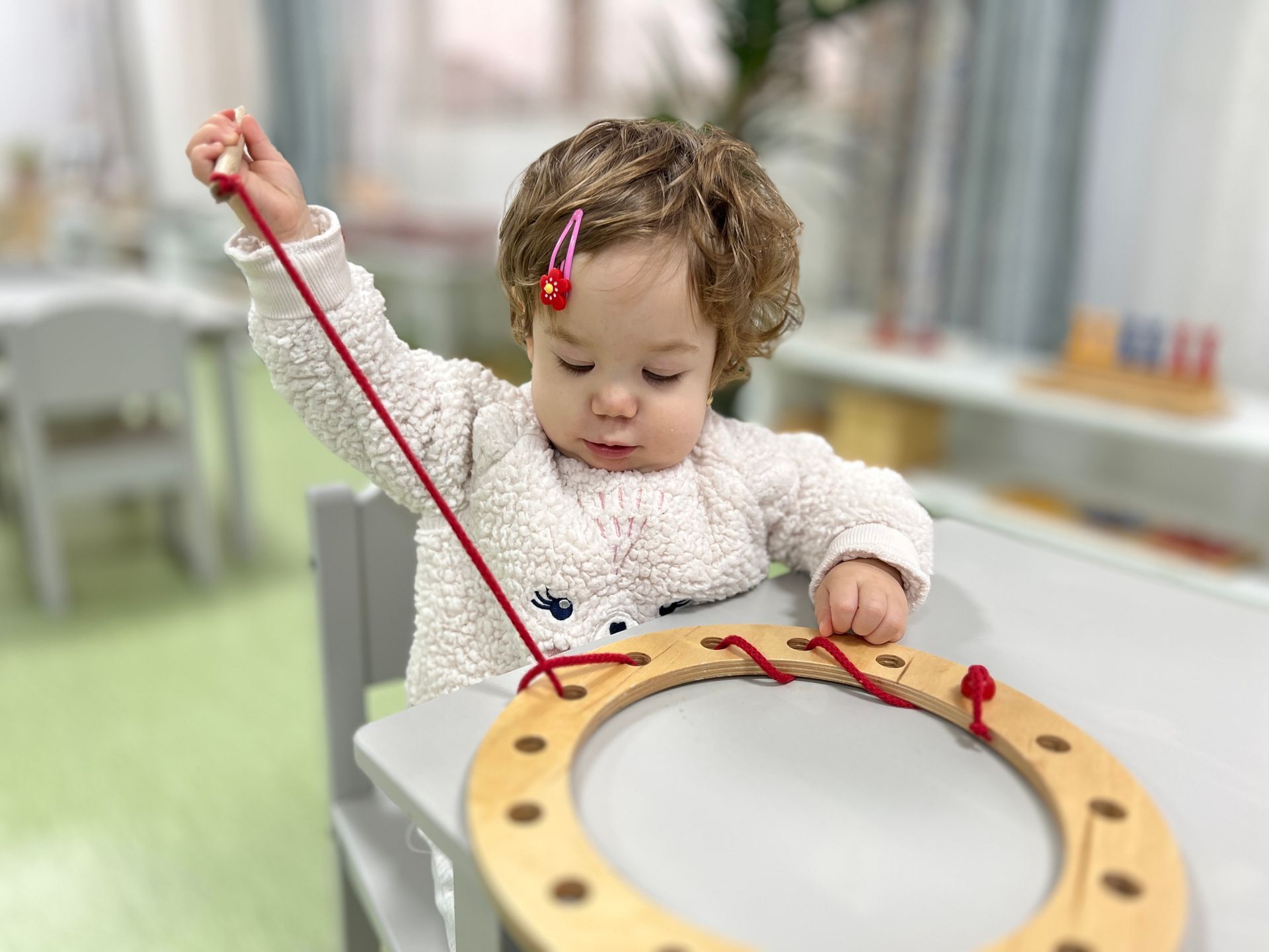 A little girl is sitting at a table playing with a wooden toy.