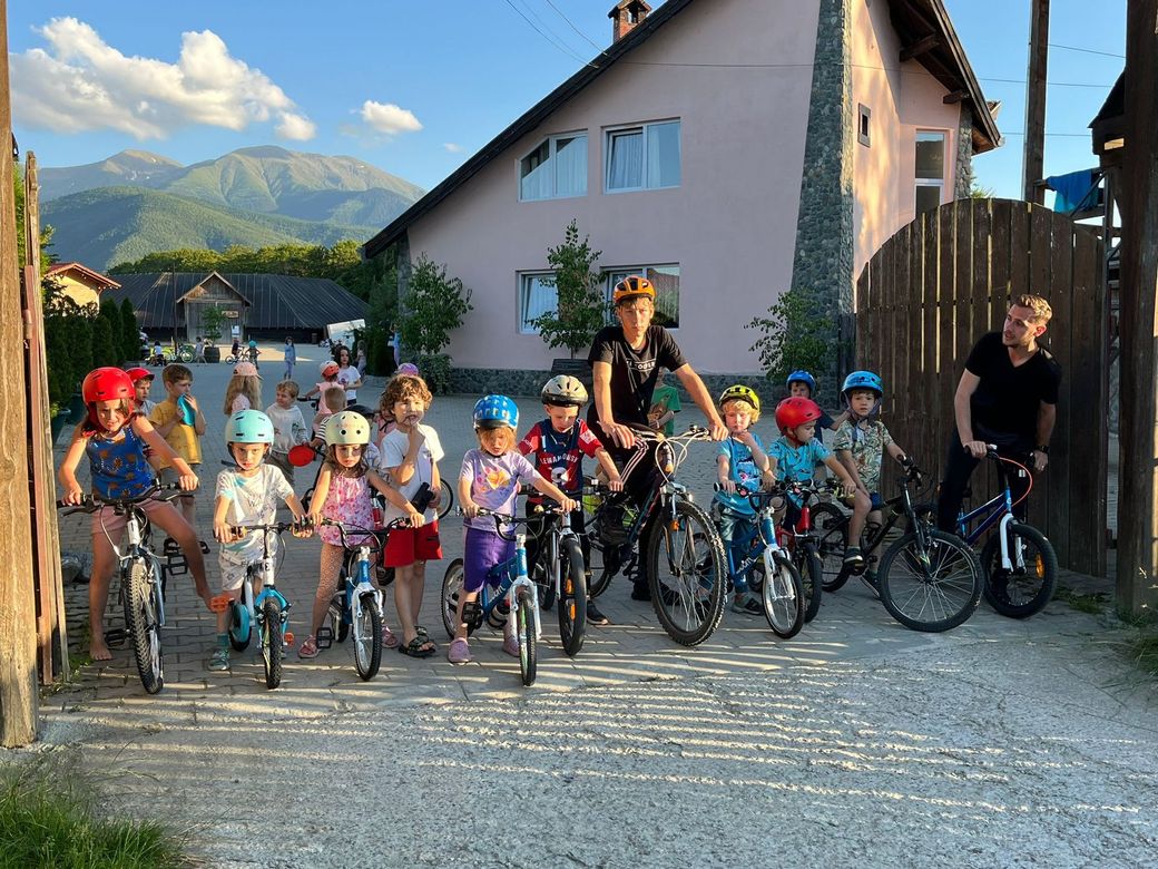 A group of children are riding bicycles in front of a house.