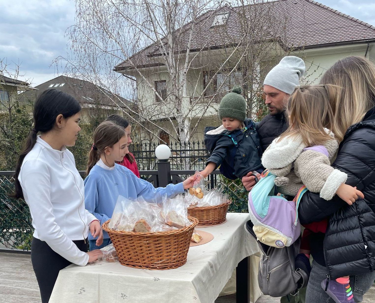 A group of people are standing around a table with baskets of food.