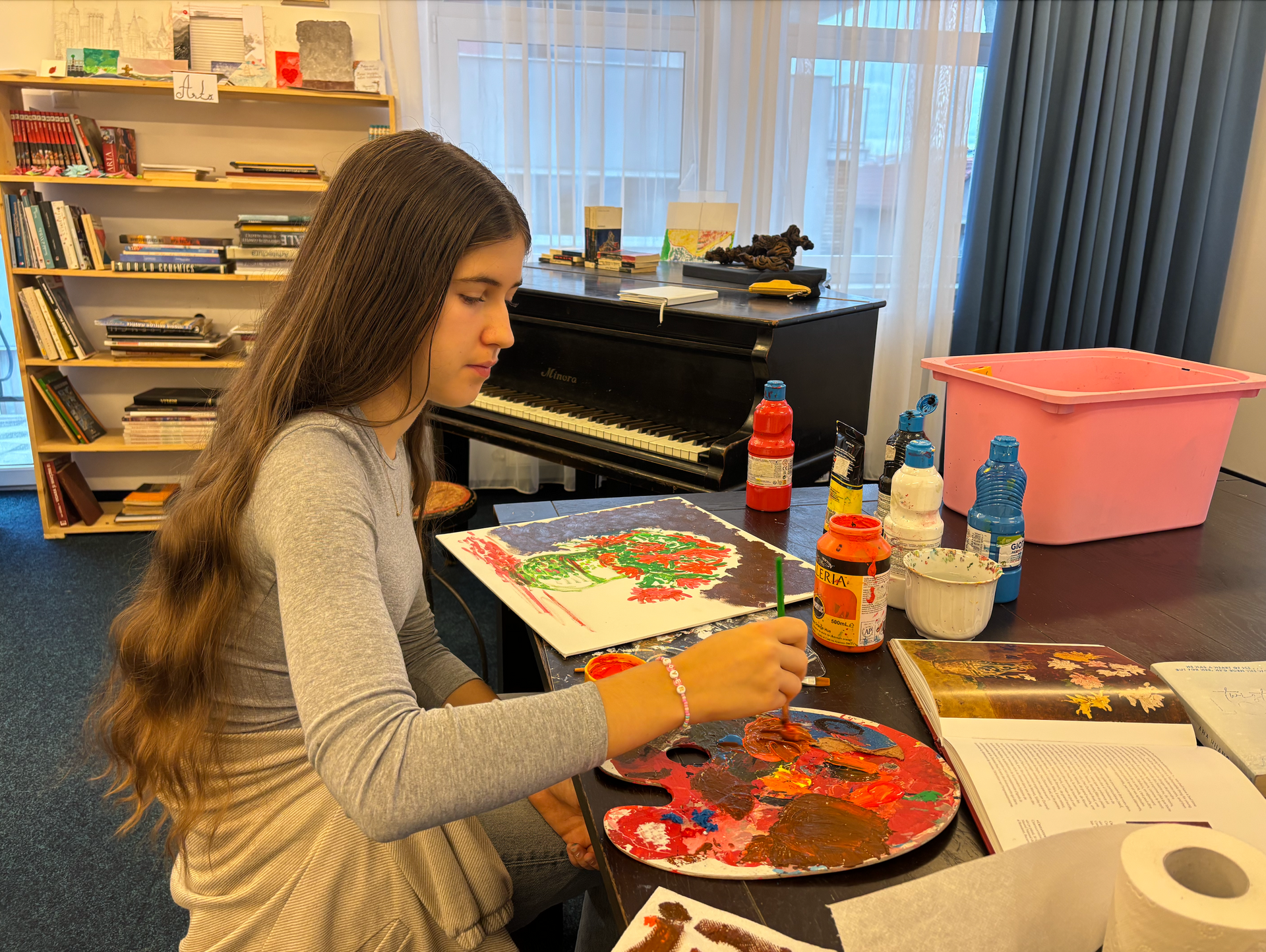 A young girl is sitting at a table painting a picture.