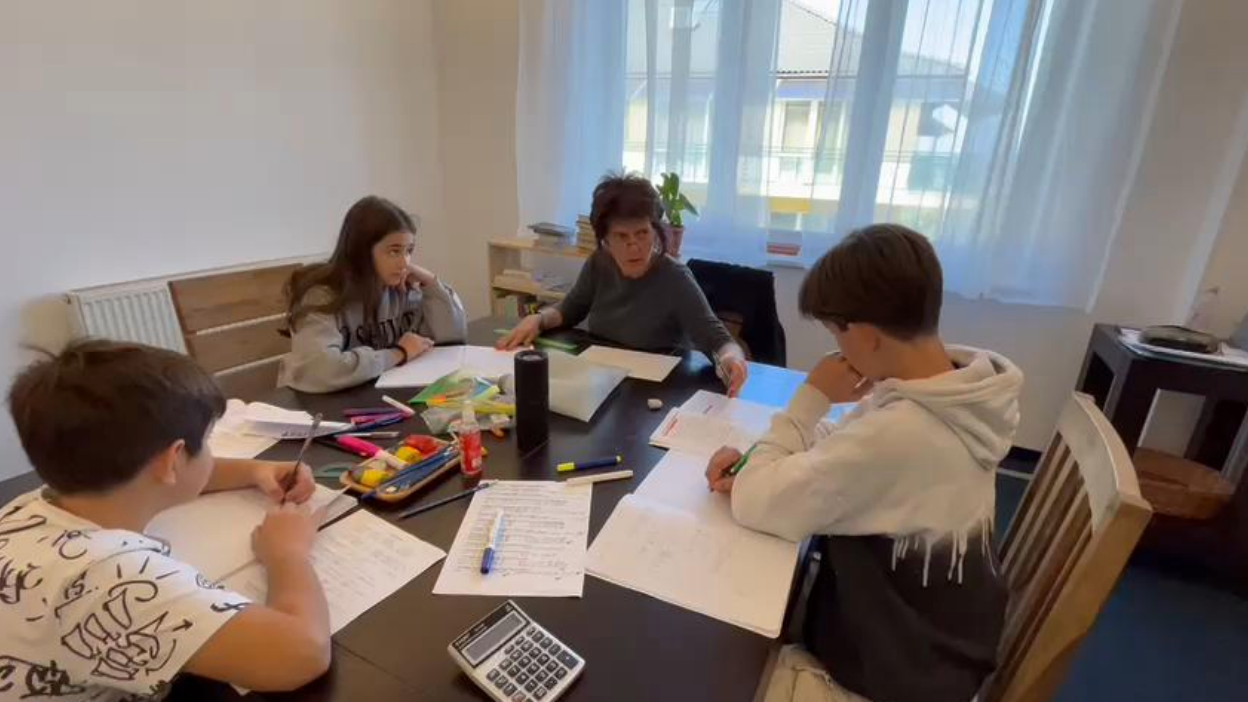 A group of children are sitting around a table doing their homework.