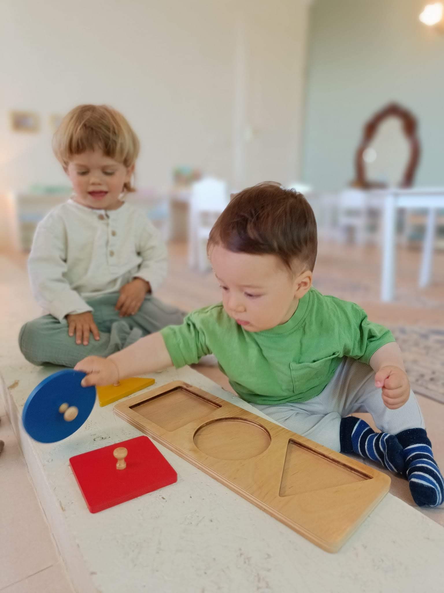 A boy and a girl are playing with toys on a table.