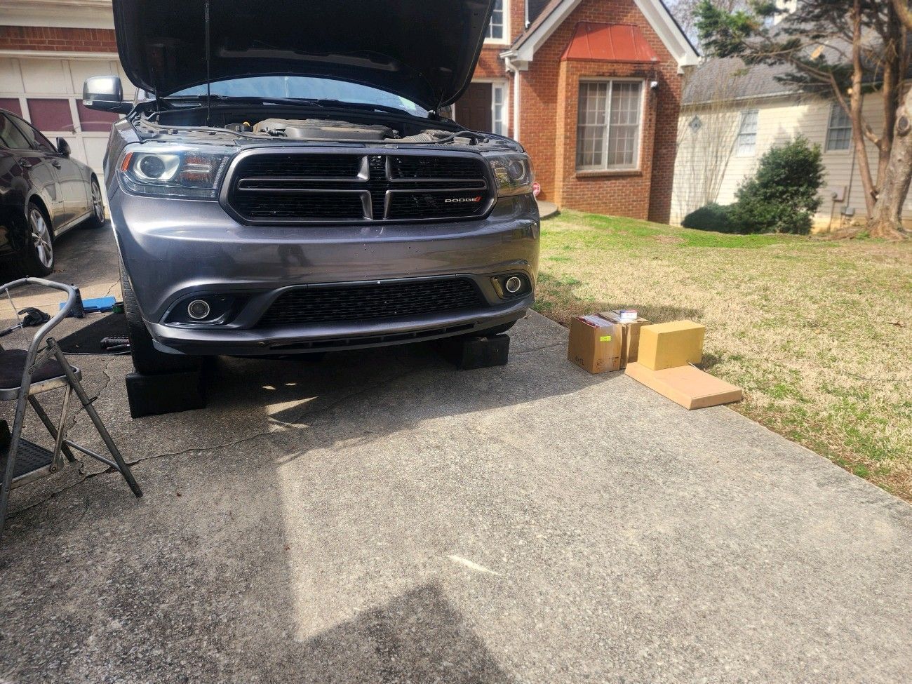 A dodge durango is parked in a driveway with the hood up.