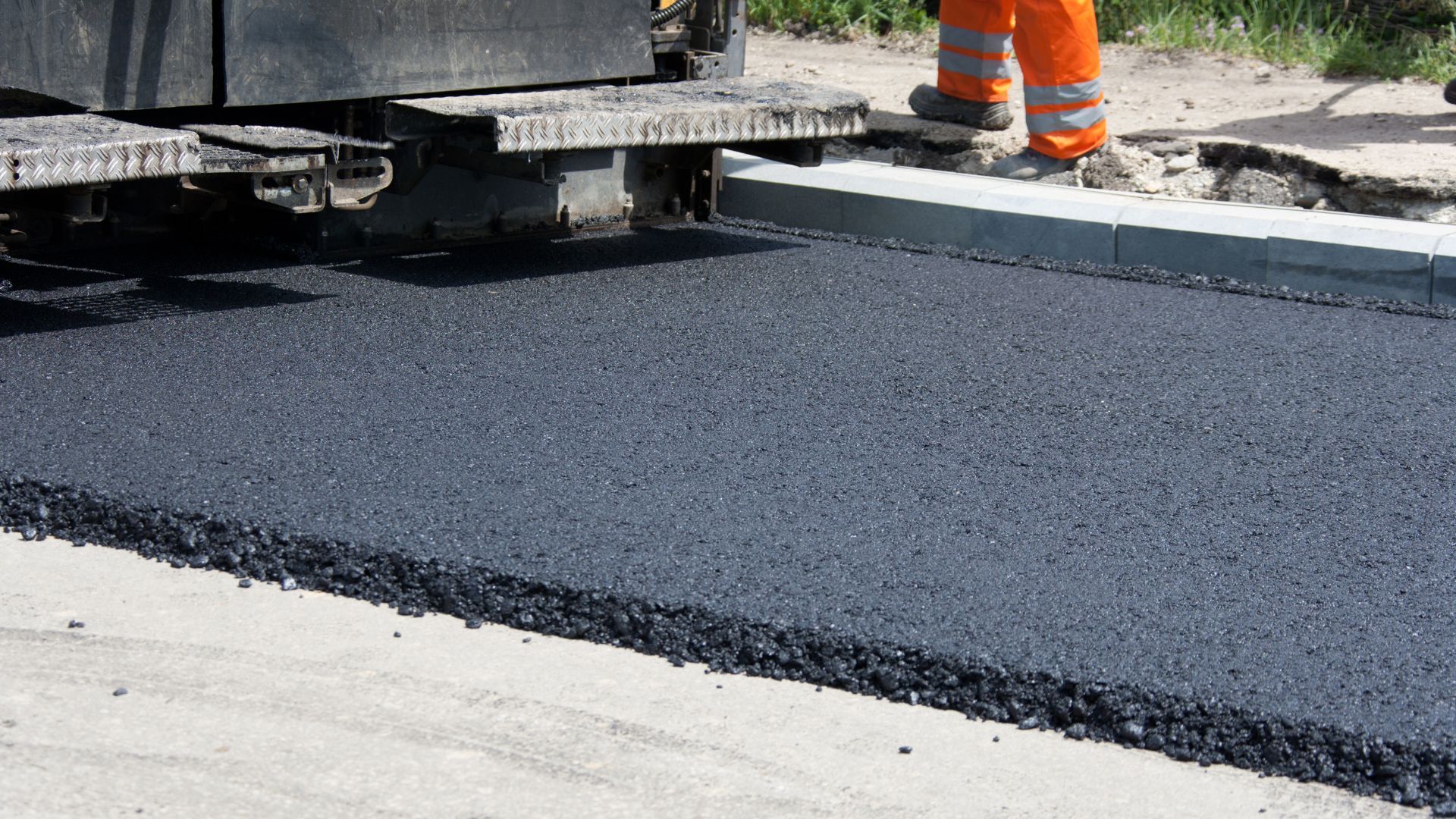 A man in orange pants is standing on the side of a road.