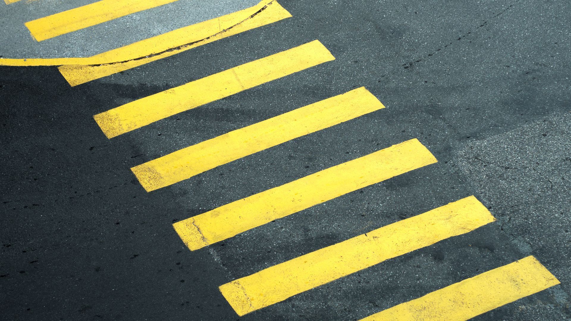 A close up of a crosswalk with yellow stripes on the road