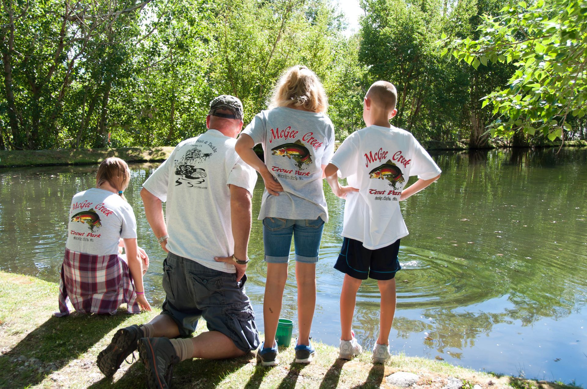 A group of people wearing shirts with fish on them are looking at a body of water