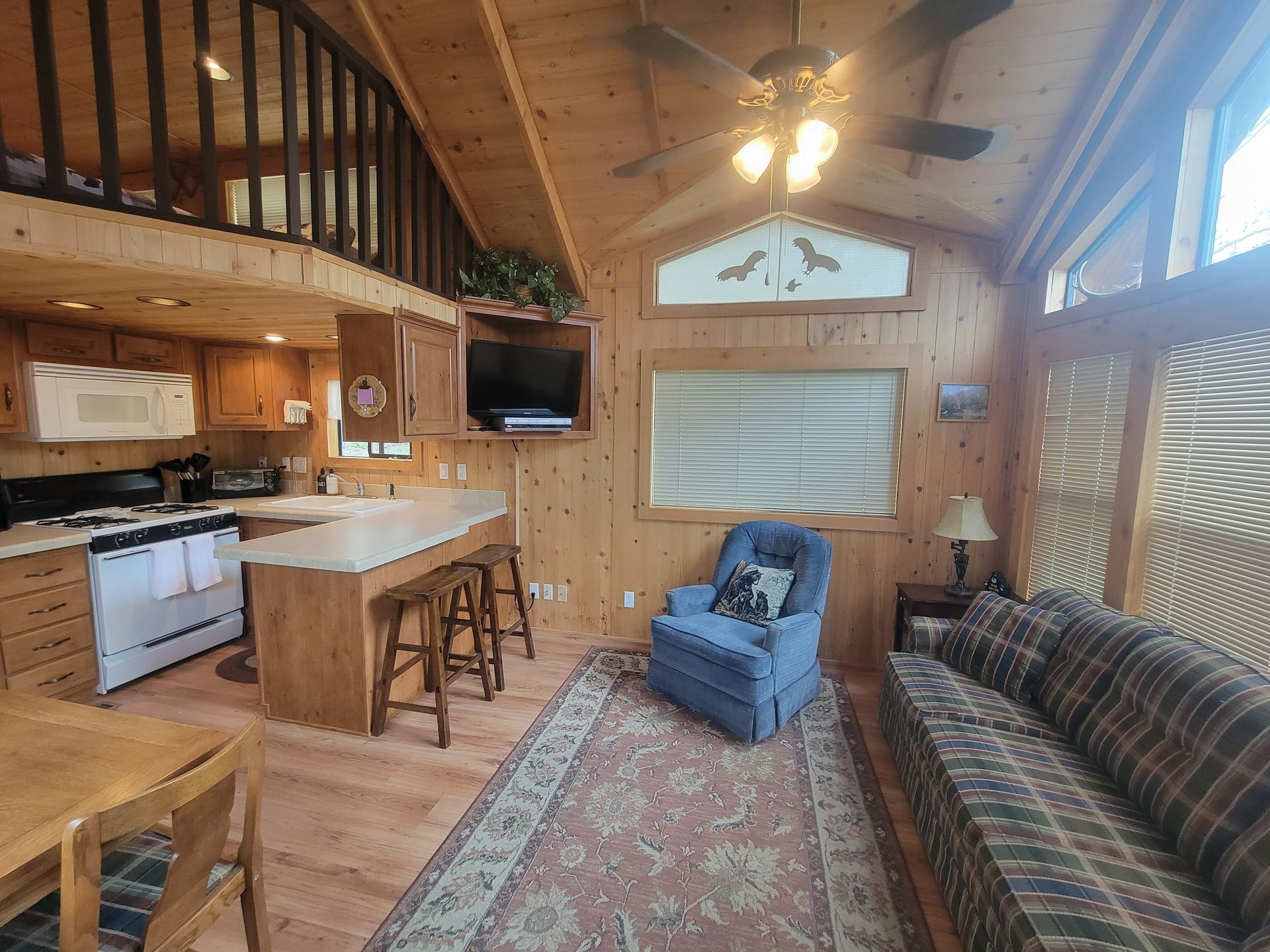 A living room with a couch , chair , table and ceiling fan.