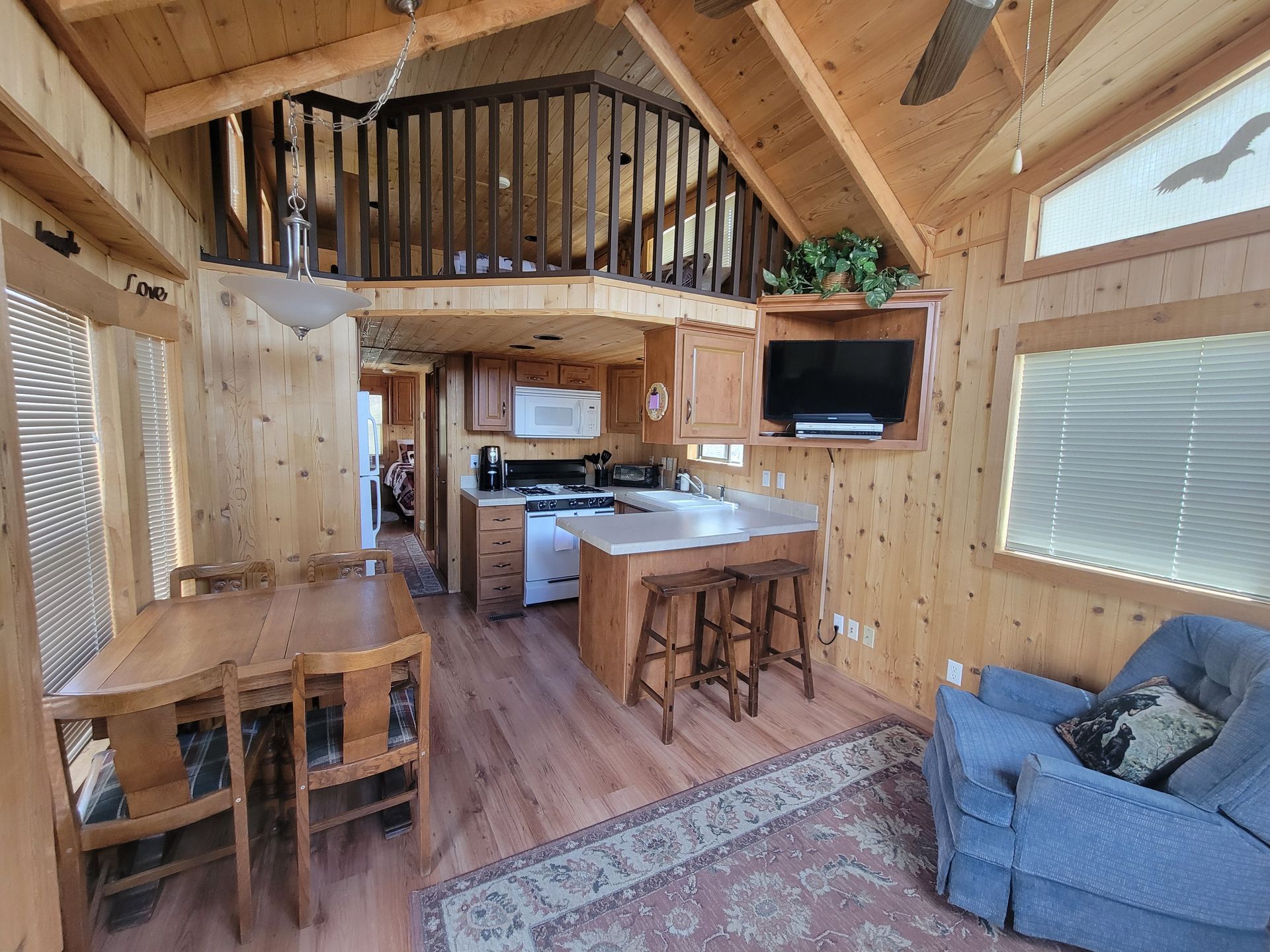 A living room with a dining table and chairs and a kitchen.