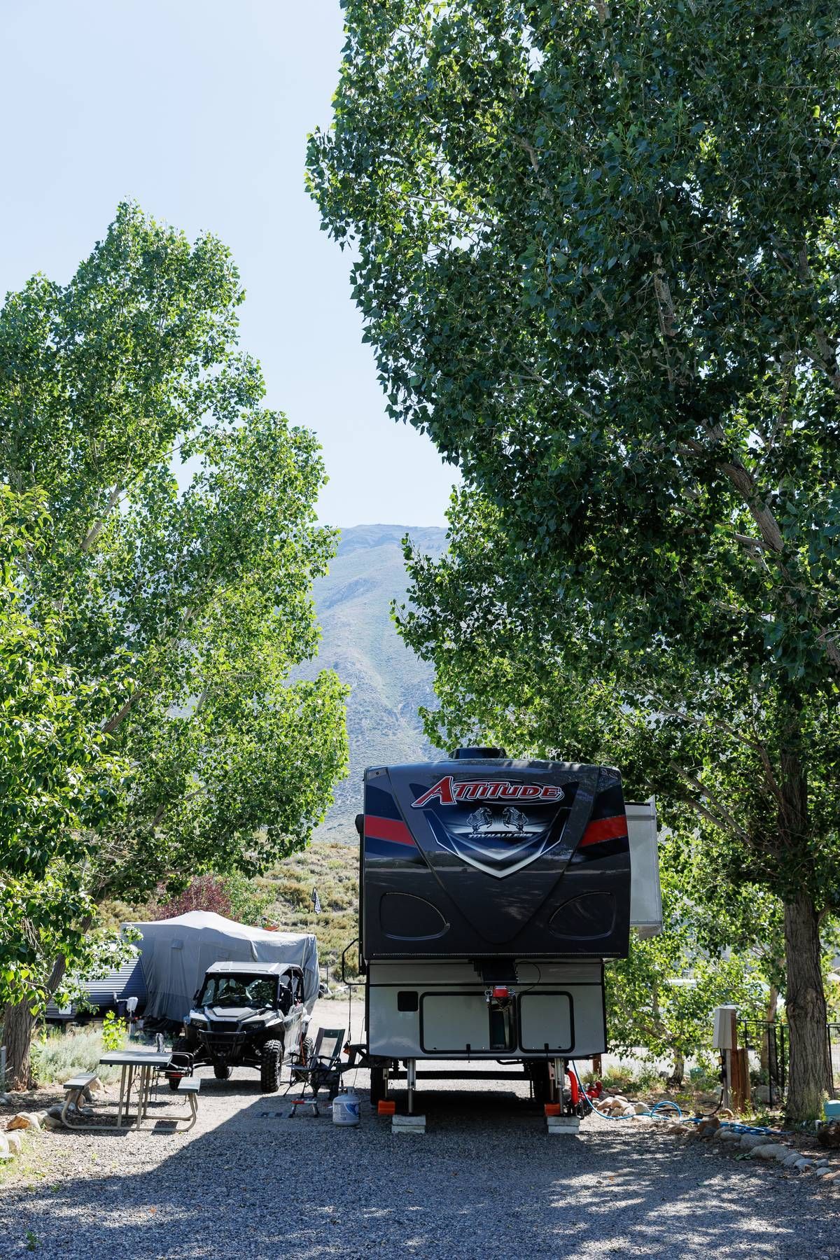 A rv is parked in a parking lot surrounded by trees.
